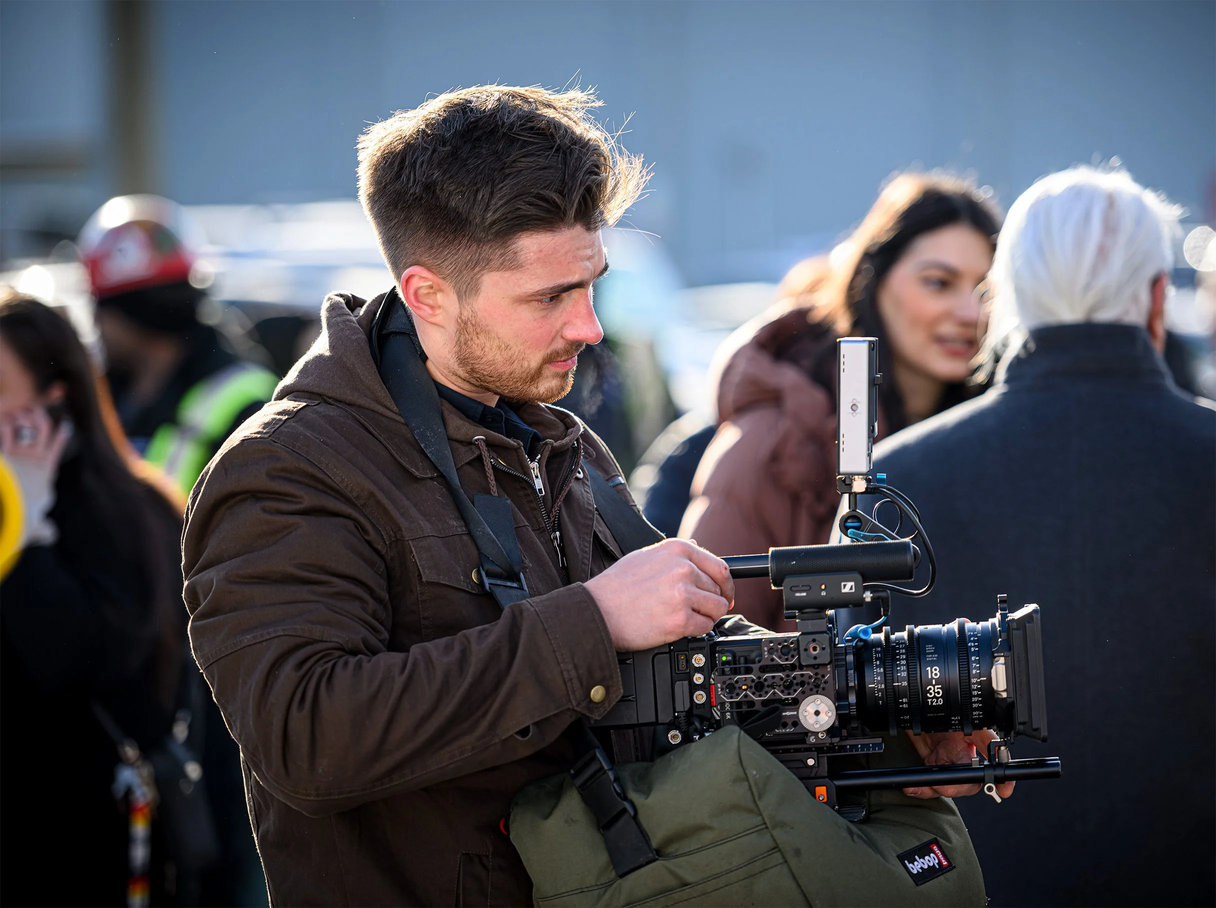 Cinematographer adjusting a cinema camera during an outdoor industrial video production.