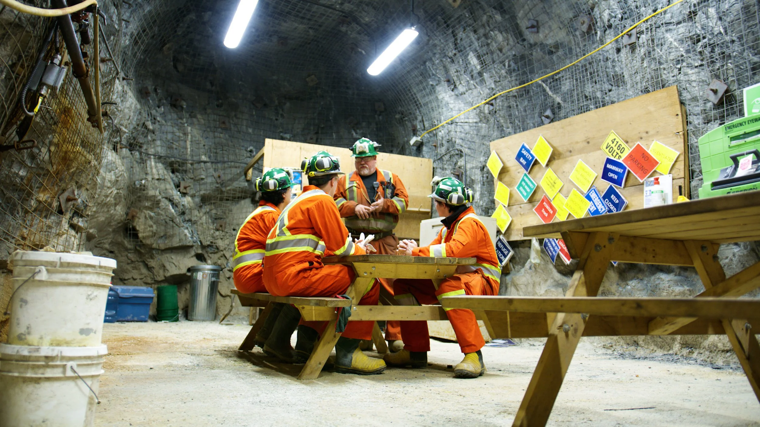 Underground mining team holding a safety meeting inside a gold mine tunnel.