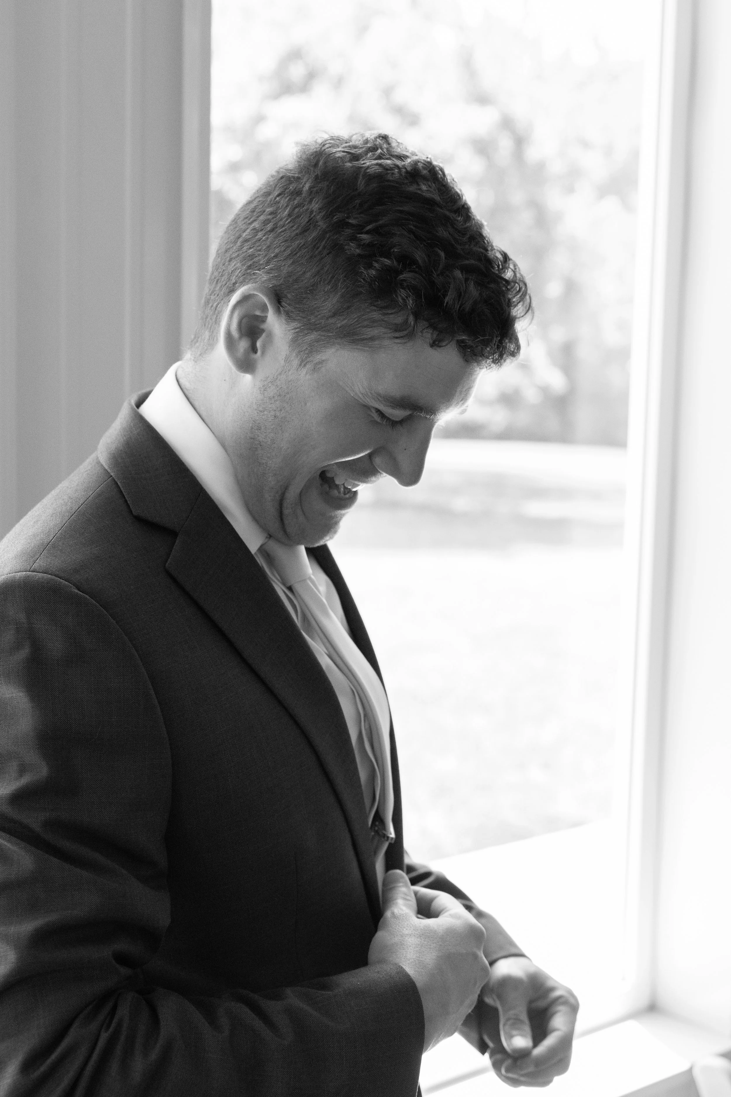 This is a scenic boho rustic view of the groom inside of The Magnolia Barn award-winning reception hall outdoor barn wedding venue featuring an exposed brick wall with natural light in Miamisburg at Magnolia Estate. Surrounded by the Greater Dayton, 