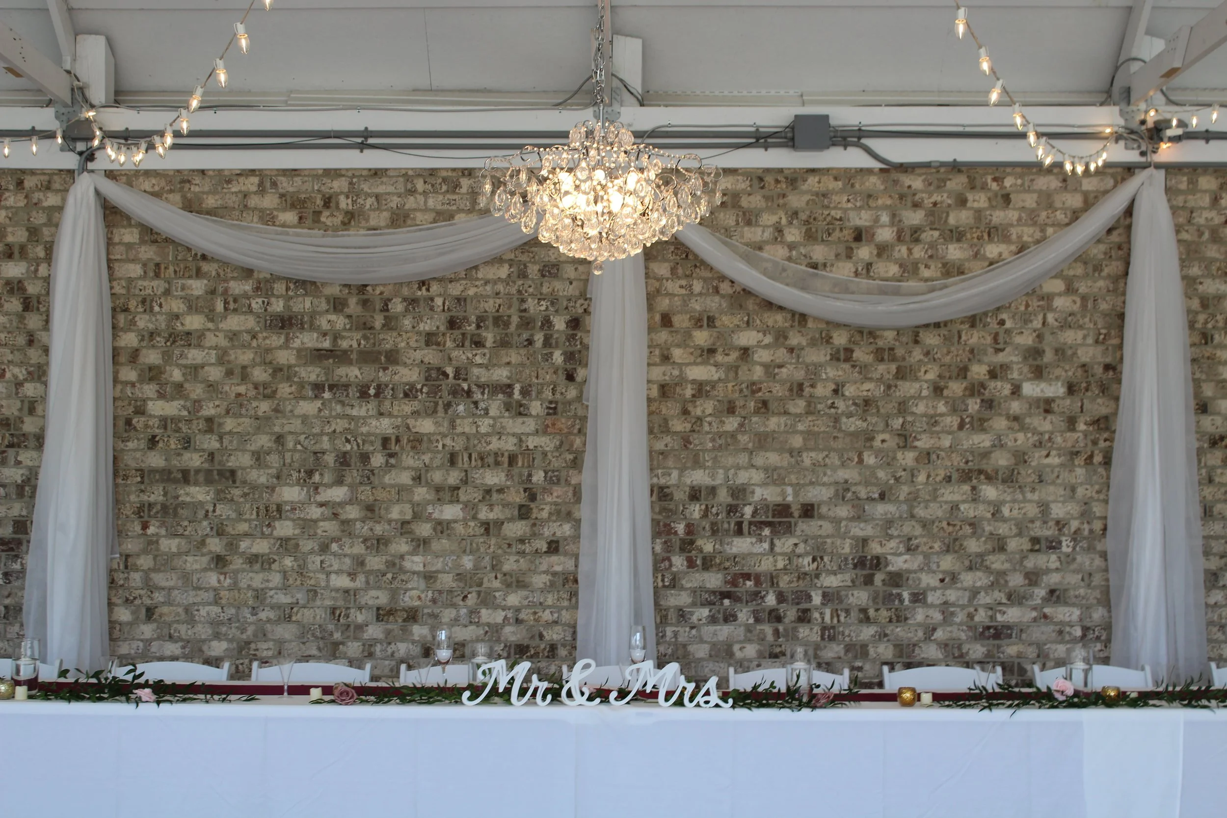 This is a scenic boho rustic view of the inside of The Magnolia Barn award-winning reception hall outdoor barn wedding venue featuring an exposed brick wall with natural light in Miamisburg at Magnolia Estate. Surrounded by the Greater Dayton, Columb
