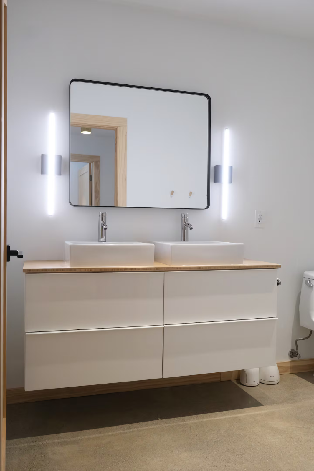 Modern bathroom with a double vanity, two vessel sinks, a large mirror, and LED wall lights.