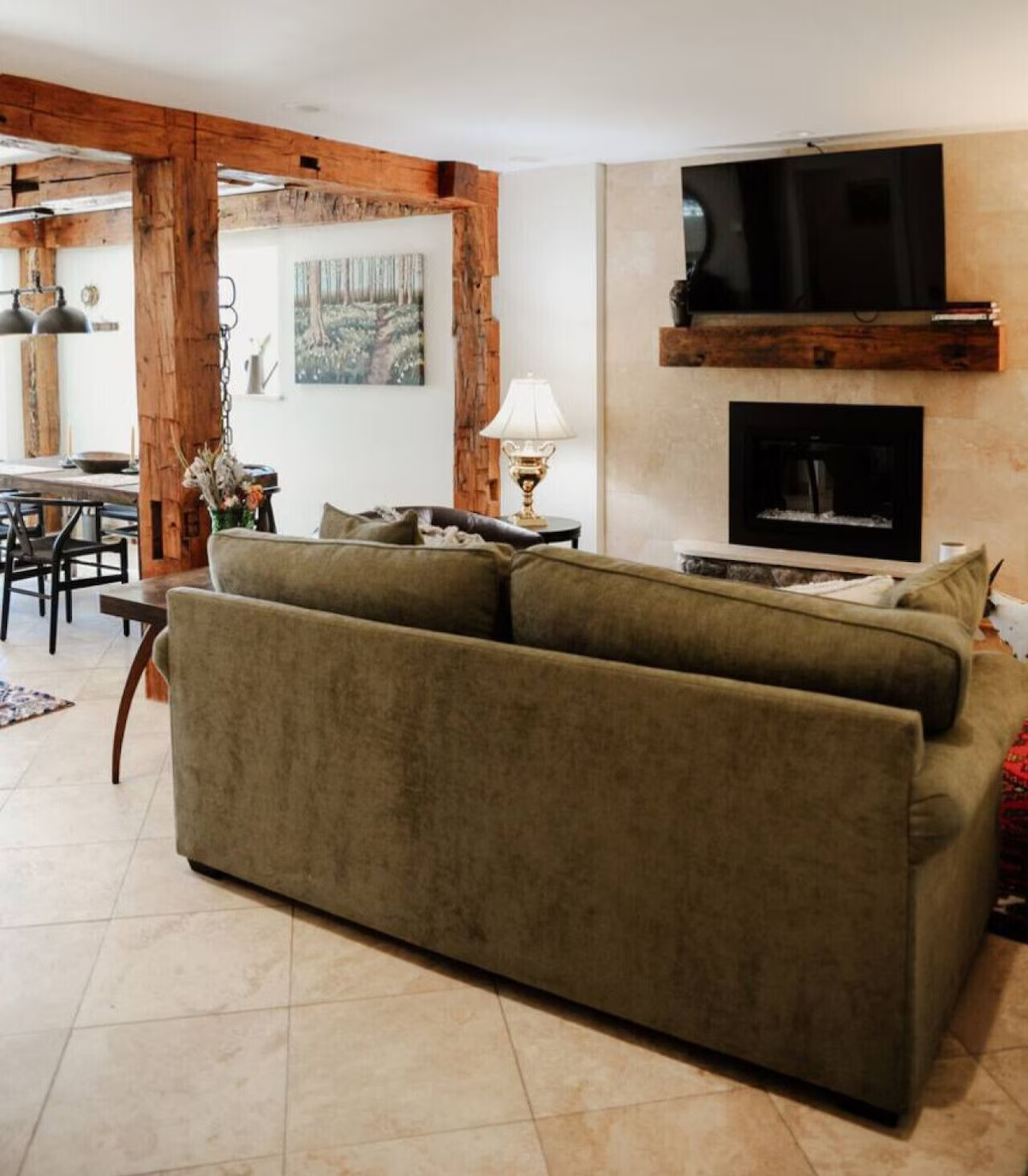 Living room with a green sofa, a fireplace, a mounted flat-screen TV, and a side table with a lamp
