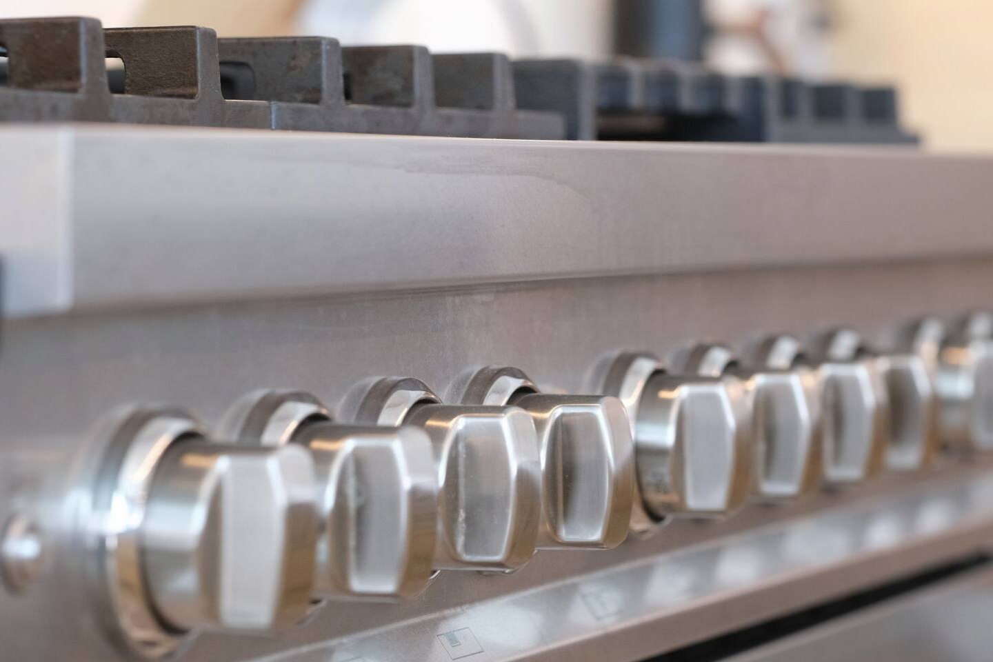Close-up of a stainless steel stove with metallic knobs and black burners.