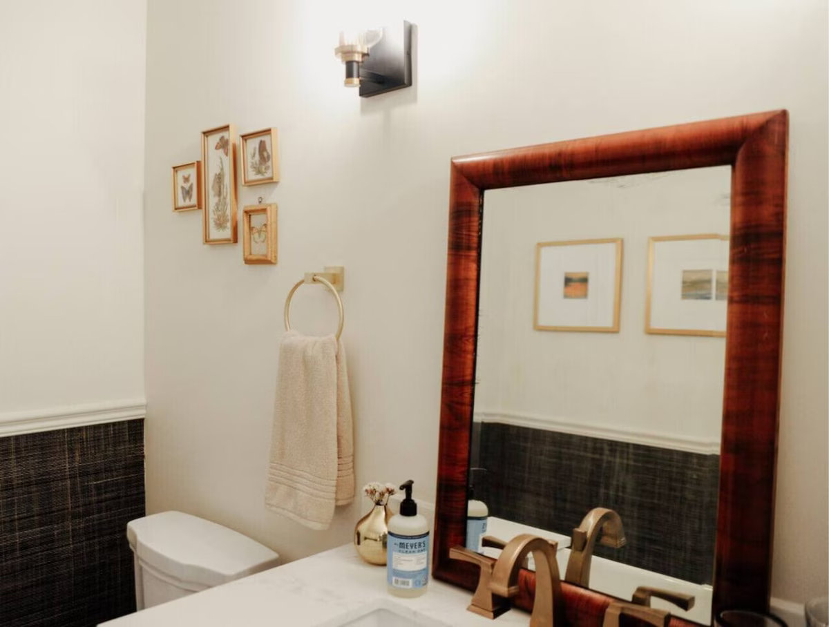 Bathroom with a mirror, framed art, a towel on a ring, and a soap dispenser on the vanity.