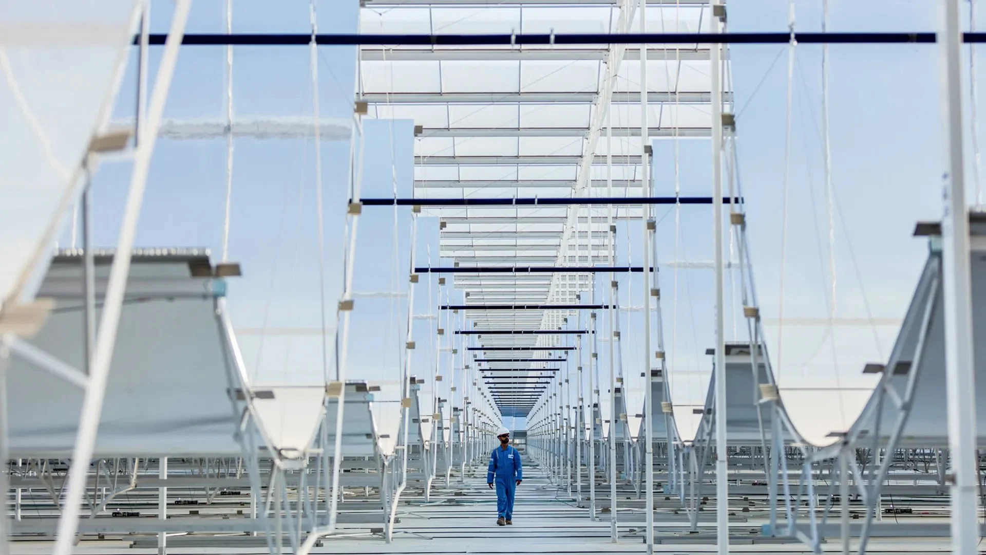 An operator walks among solar troughs at a large-scale GlassPoint Solar installation in Oman.