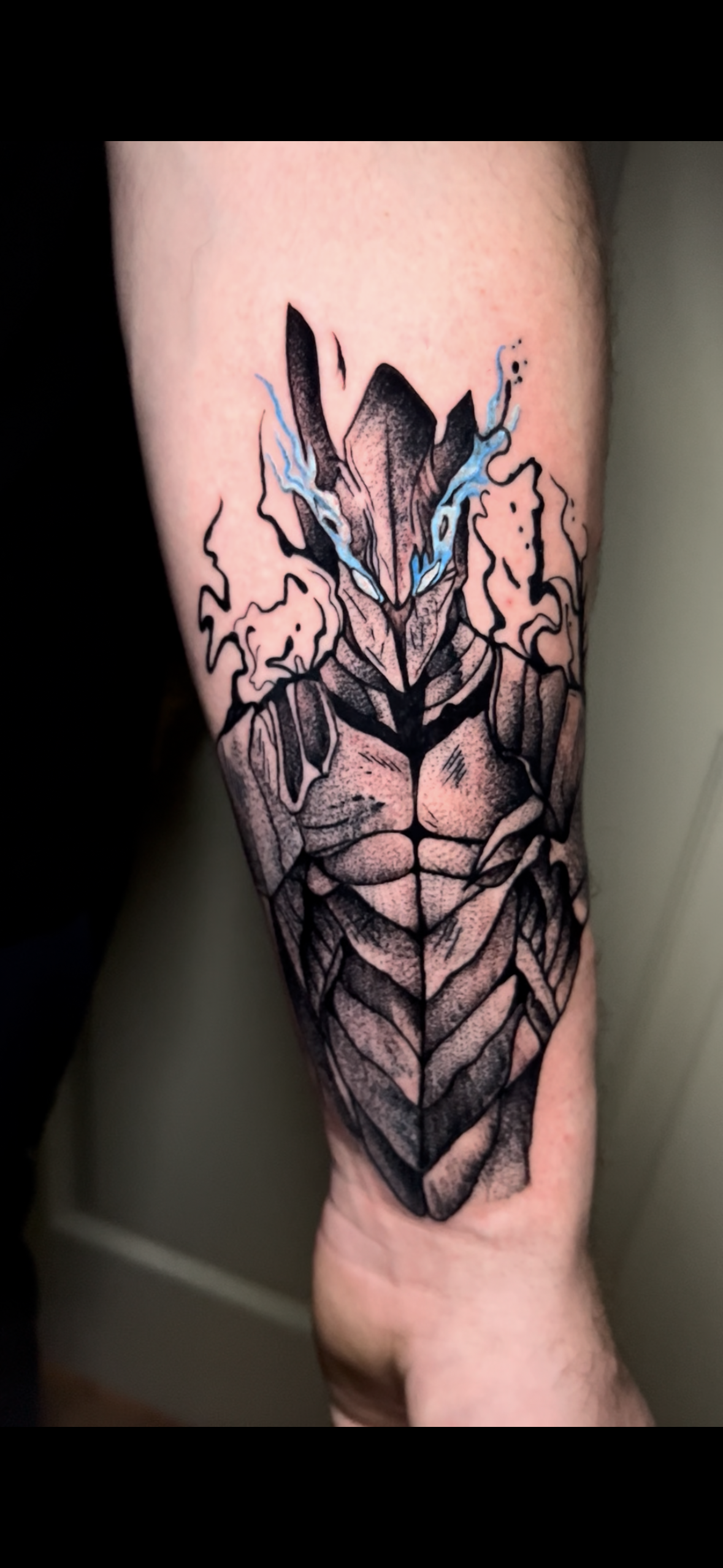 Tattoo of a wolf's head with water or lightning effects on the face, and geometric patterns extending down the arm.