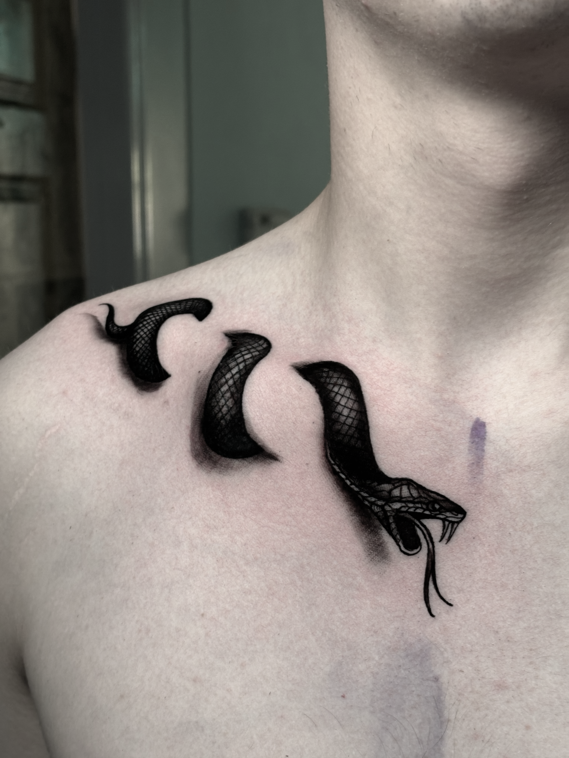 Close-up of a person's neckline showing a black lace tattoo design.