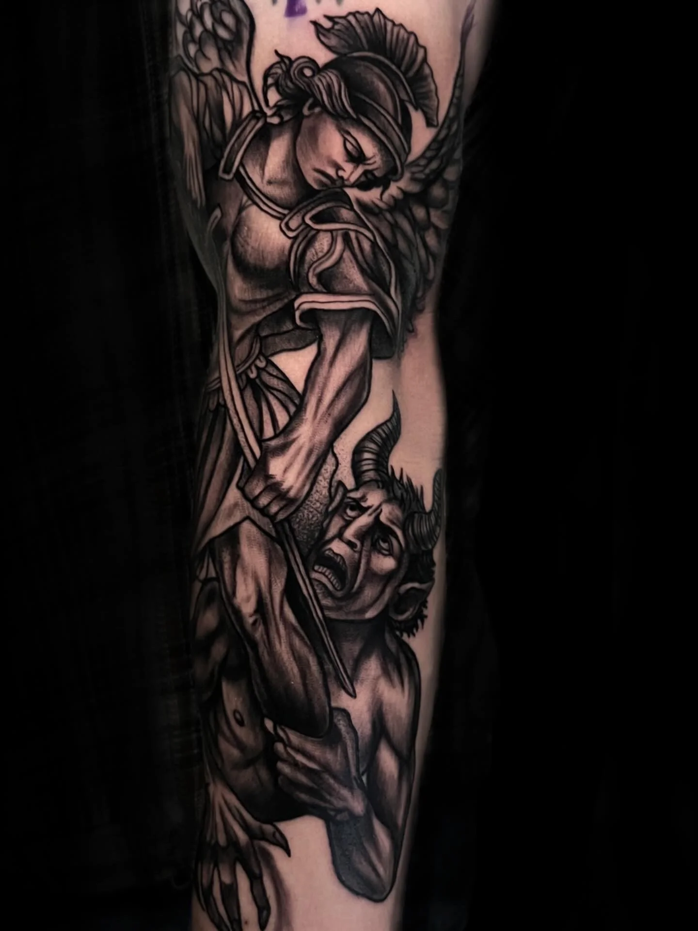 Black and gray tattoo of a woman with a helmet riding a horse, with the woman looking down with eyes closed, on a person's arm.