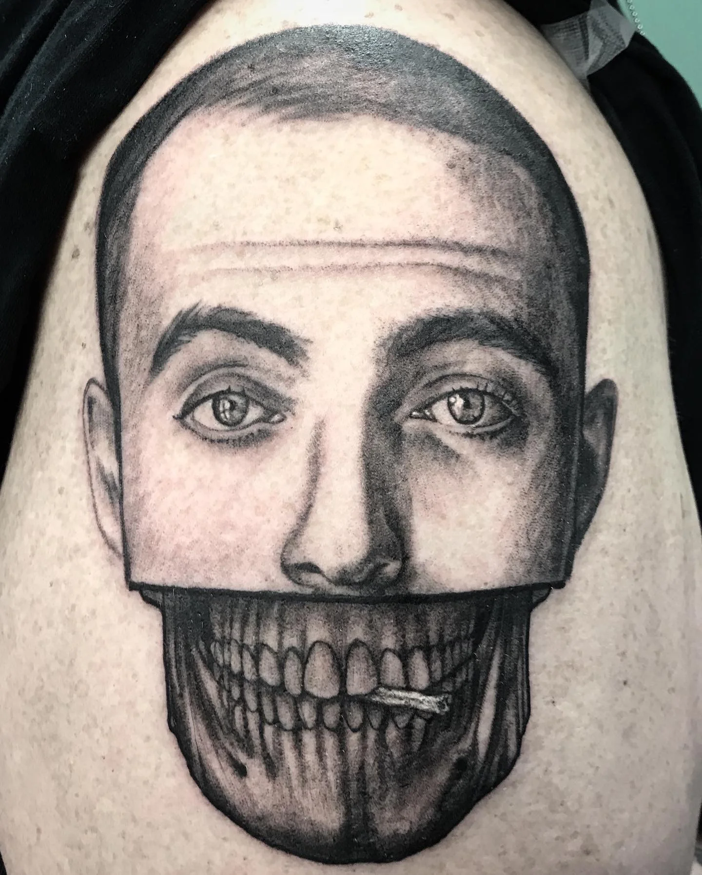 Black and gray portrait tattoo of a person's face with eyes, eyebrows, nose, and lips, combined with a human skull under the chin, blending the face and skull seamlessly.