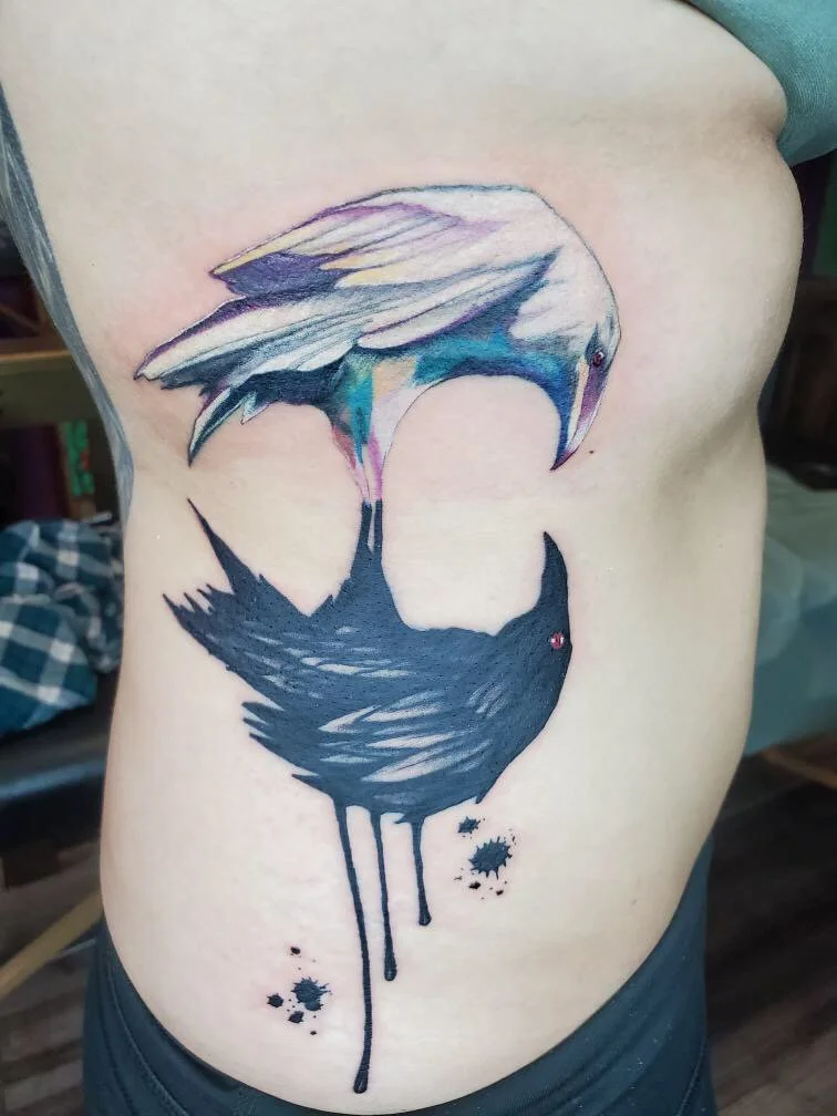 Tattoo of a black heron with a colorful, abstract waterfall-like wing design on a person's side.