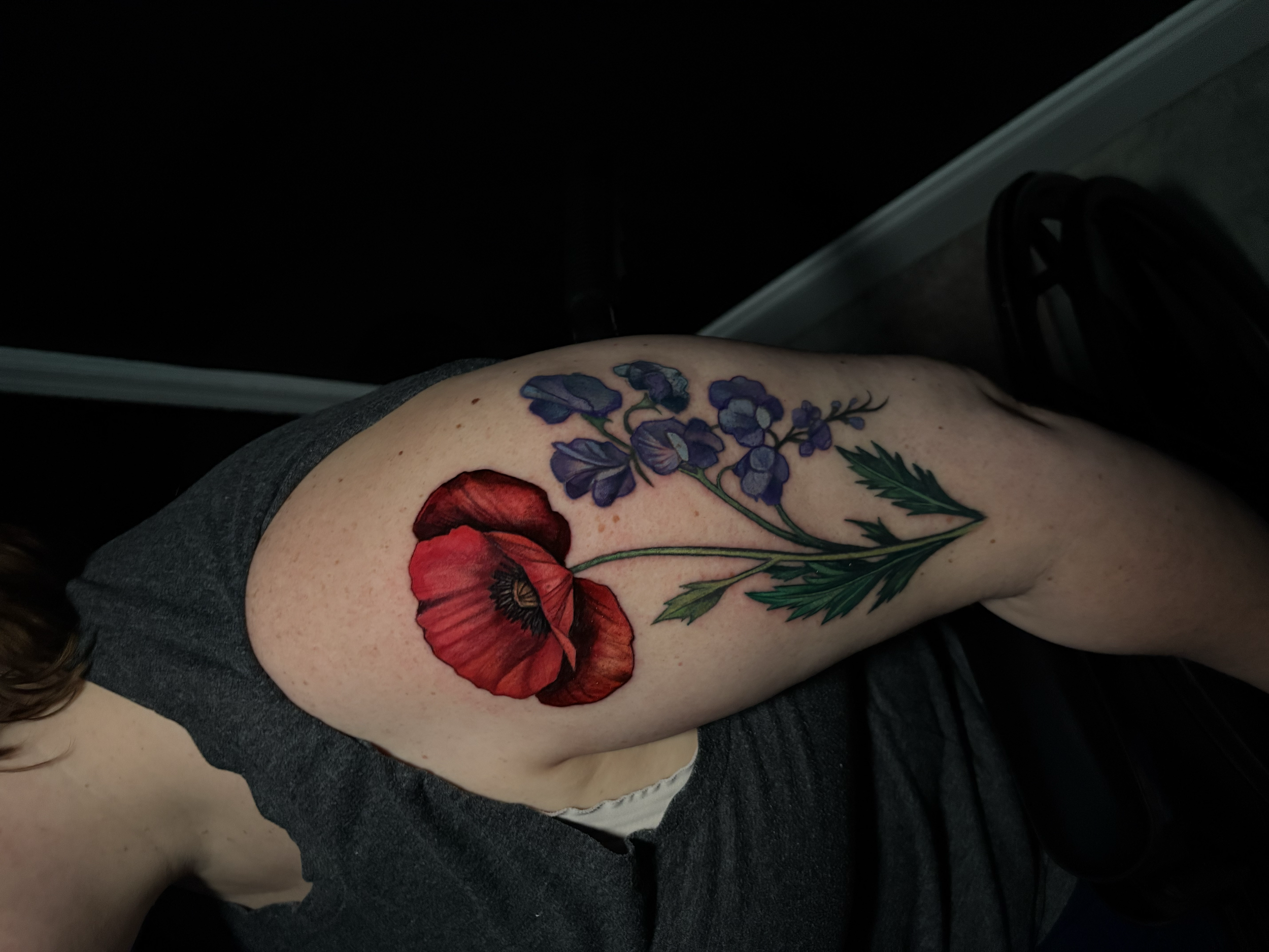 Color floral tattoo featuring a red poppy and blue wildflowers by tattoo artist Salvador Vargas III