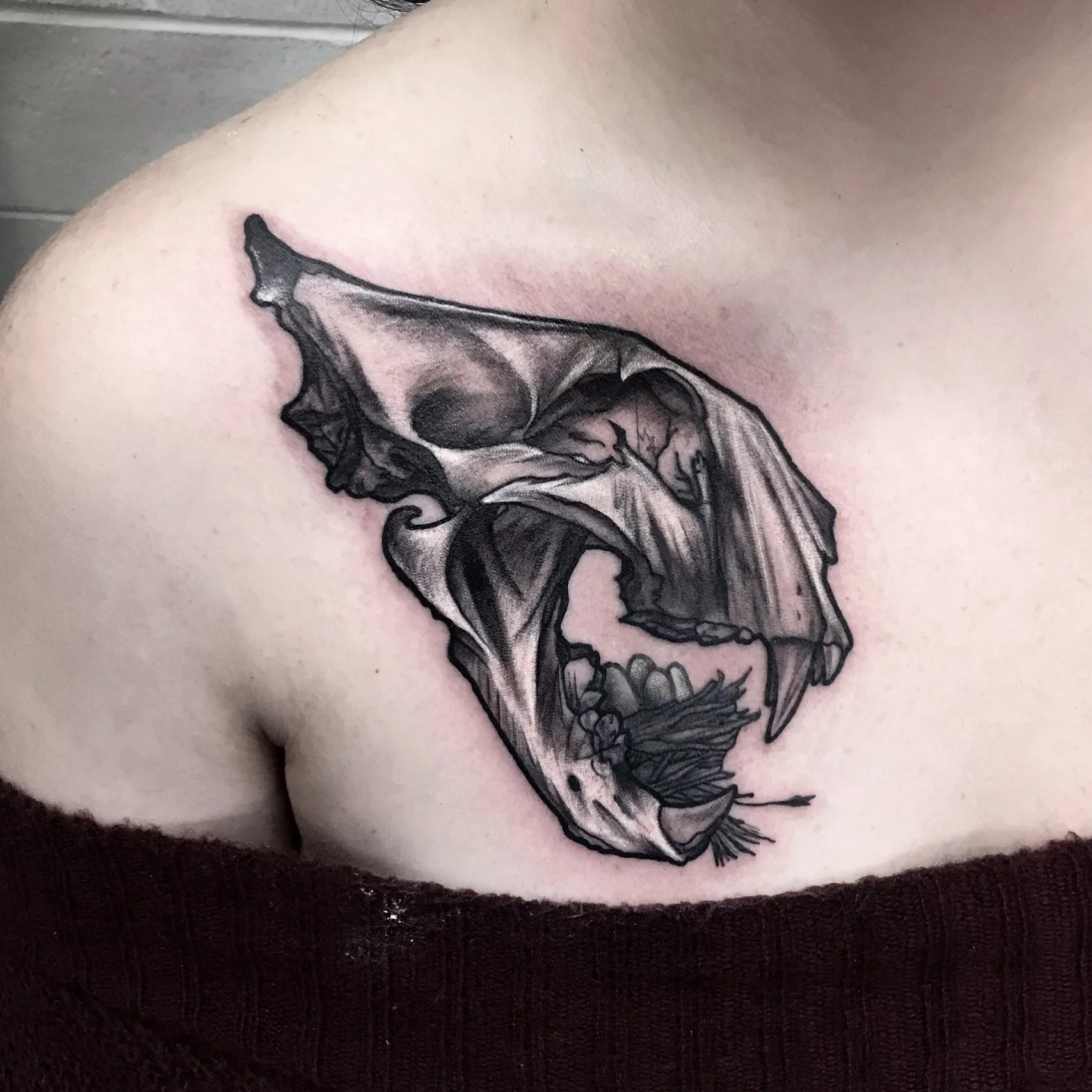 Black and gray tattoo of a bird skull on a person's upper arm and shoulder.
