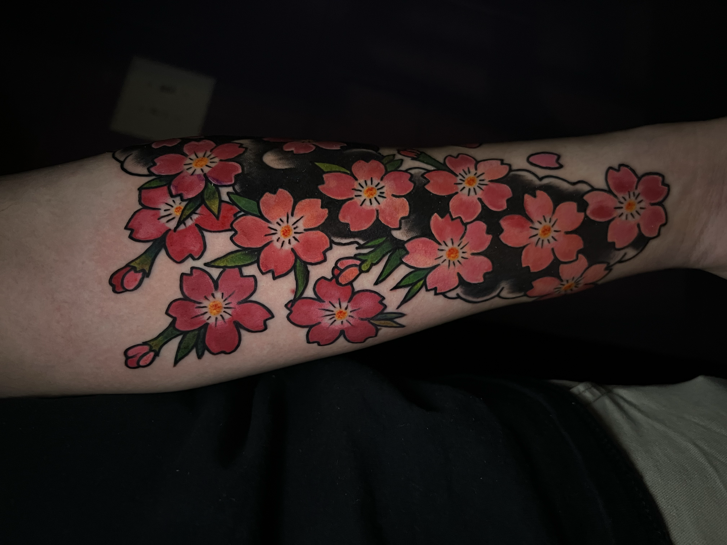 Japanese cherry blossom tattoo with vibrant pink and red sakura flowers, green leaves, and bold black linework by Salvador Vargas III, serving Bluffton SC, Savannah GA, and Charleston SC.