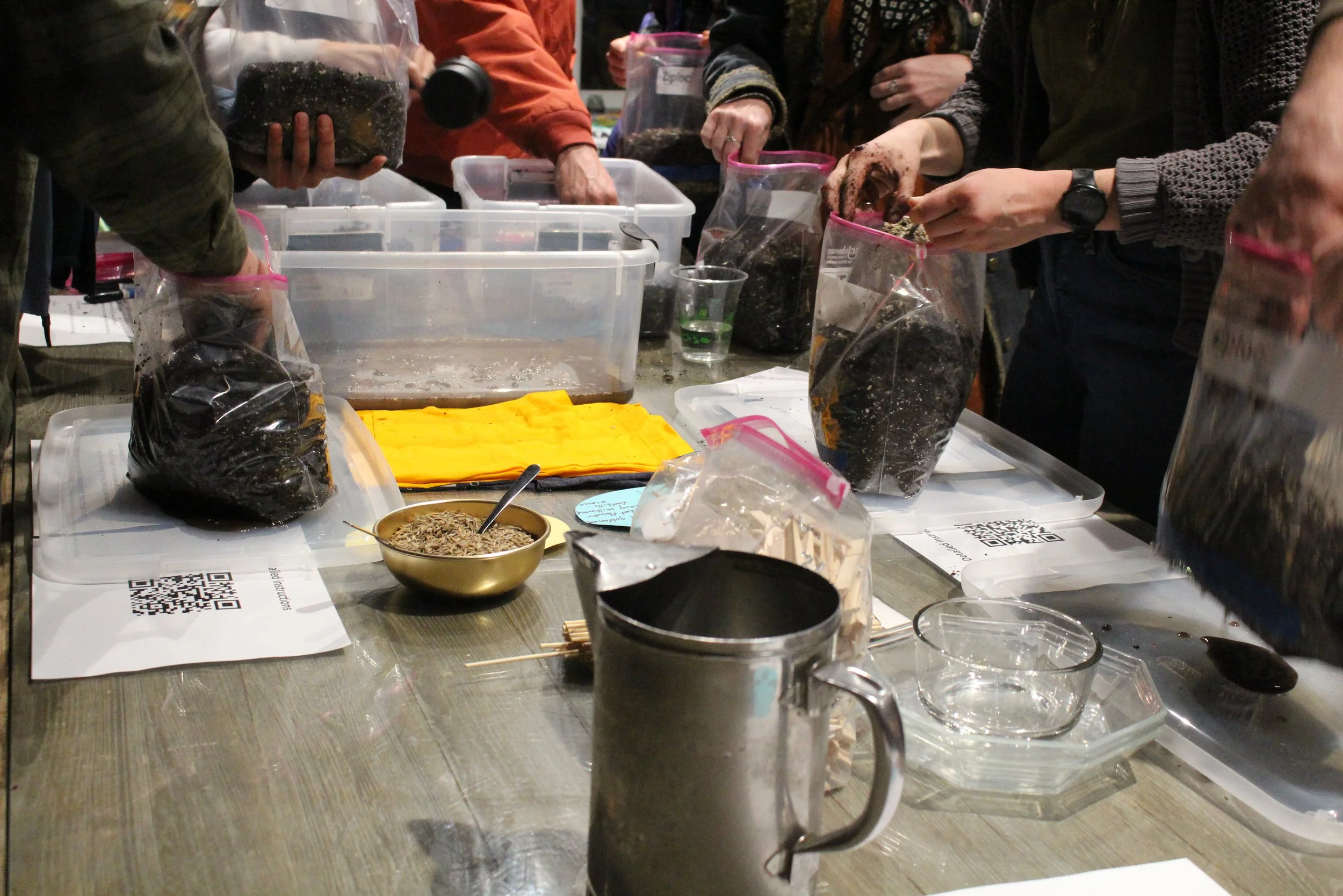 People filling up bags with soil and seeds. supplies spread out on a table.