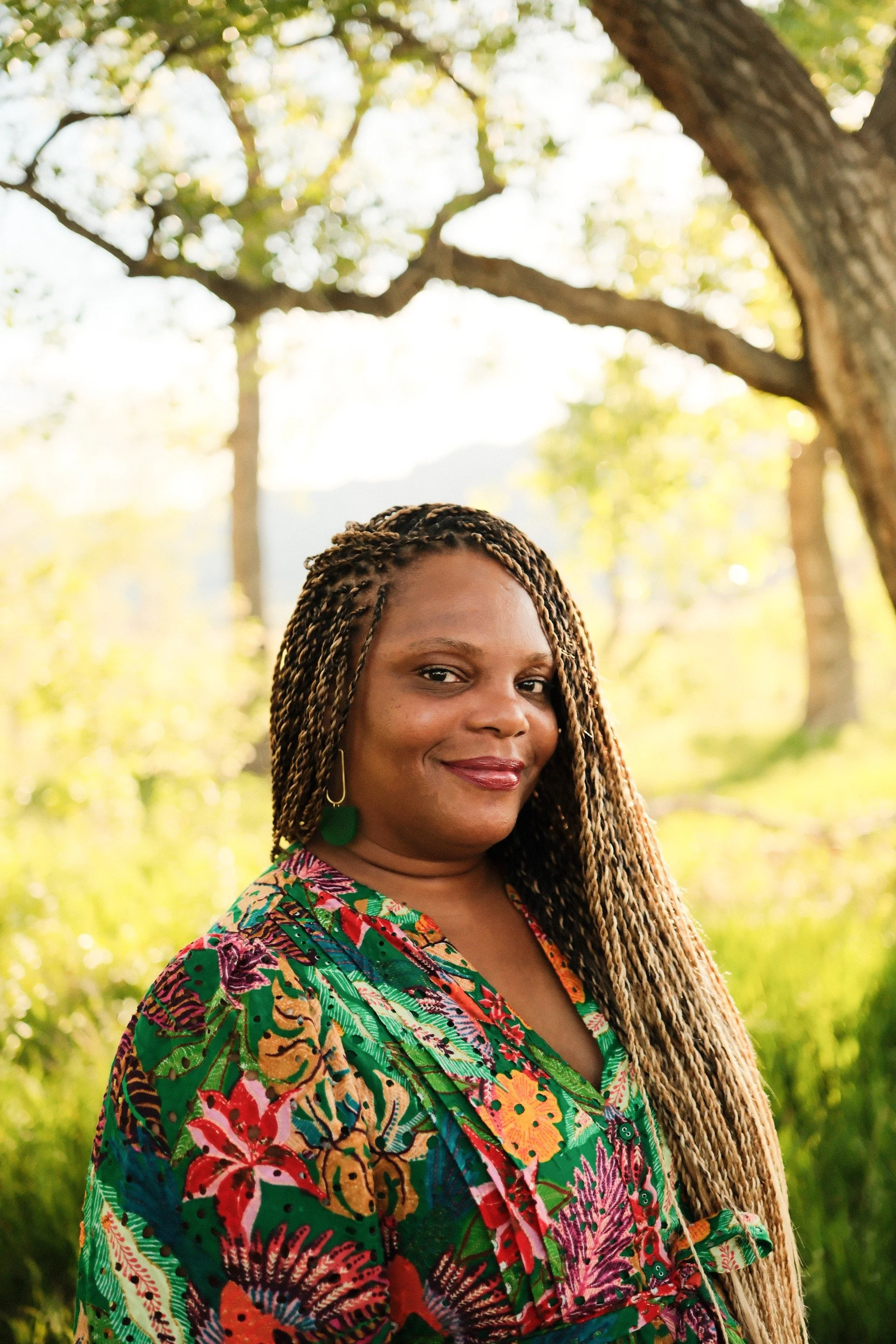 Black woman with braids and nature behind her.