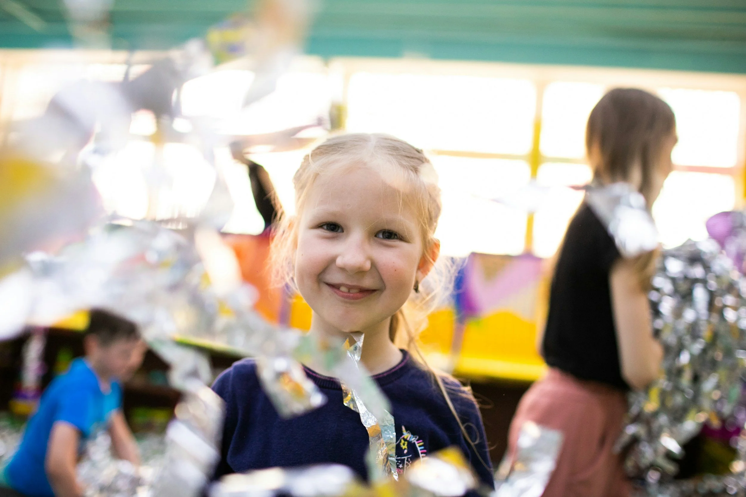 Little girl smiles at camera through pom poms