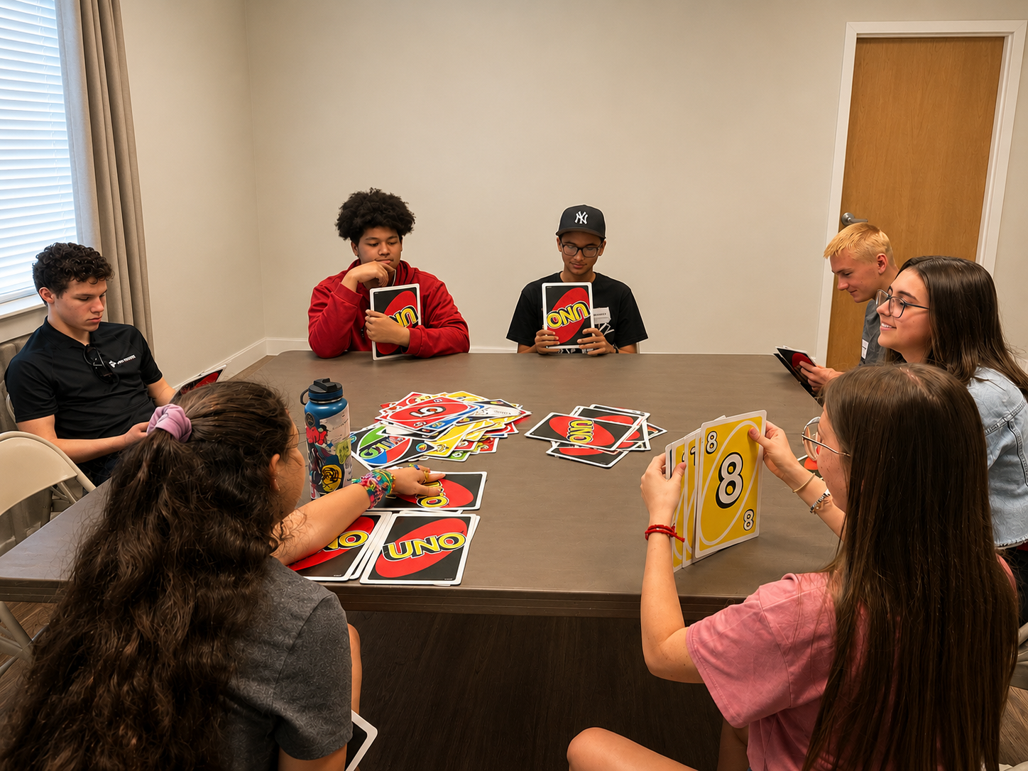 students sit at a table together playing UNO.