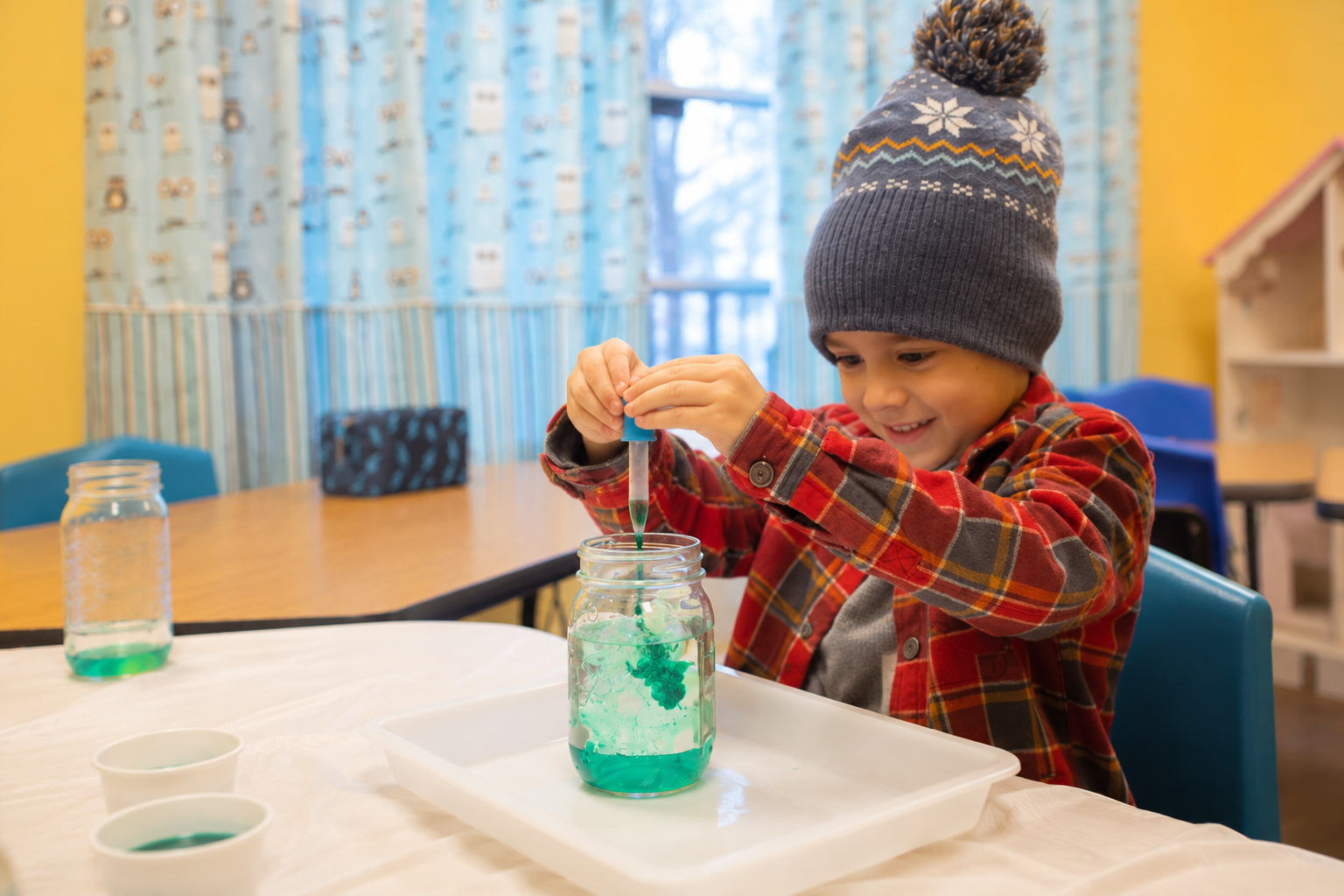 little boy squeezes coloring into jar of water and oil sitting at table.