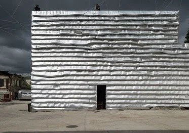 EMA Space by Kosmos Architects. The layered silver facade is made from common insulation foil, normally used in construction for covering air ducts and vents.