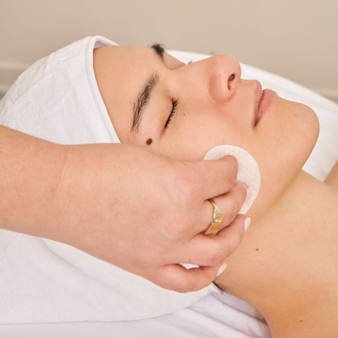 image of white woman getting a peel pad brushed across. her face during a facial