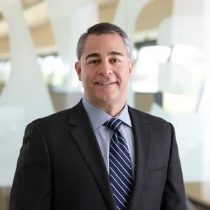 Smiling man in a suit and tie in an office setting.