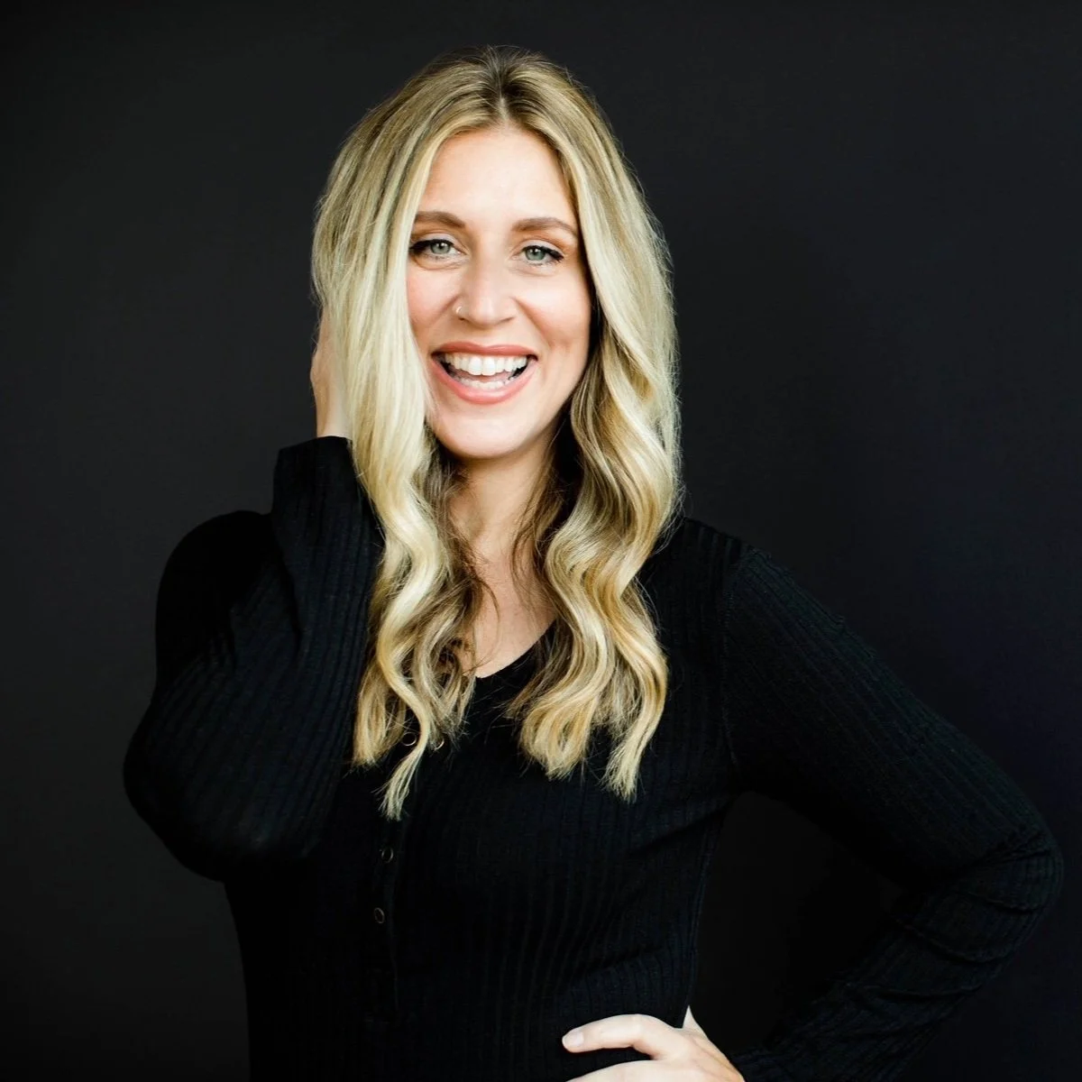 Smiling woman with long blonde hair against black background