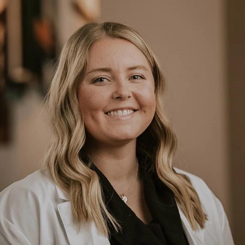 Smiling woman with blond hair wearing a white coat.