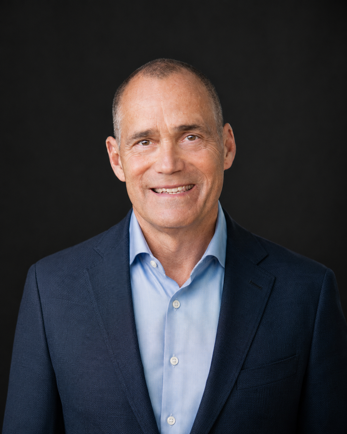Smiling man in a suit and tie against a plain background.