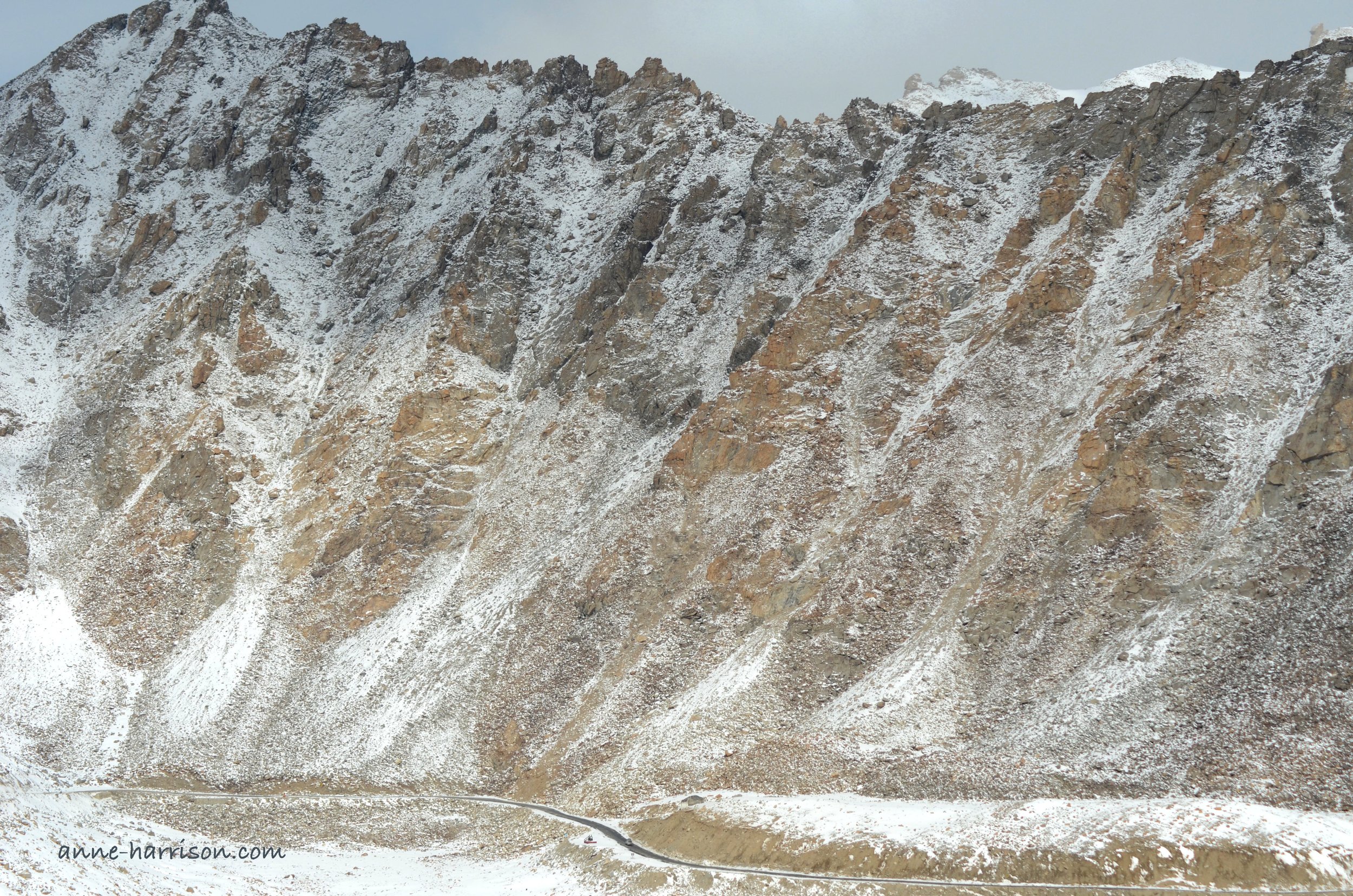Snow capped mountains dwarf the highway running at their feet.