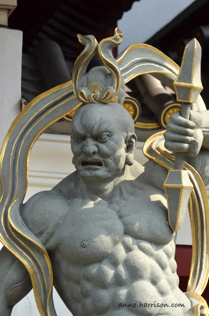 A fearsome statue of a temple guardian with gold decoration