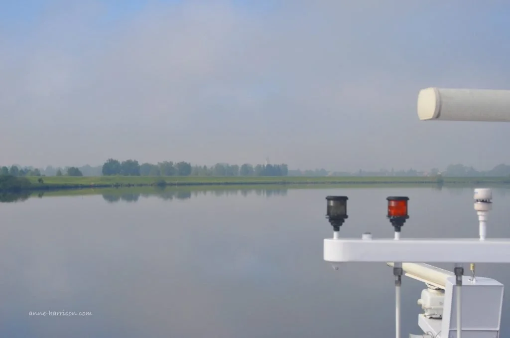 A view over the navigation system of a boat towards a distant river bank