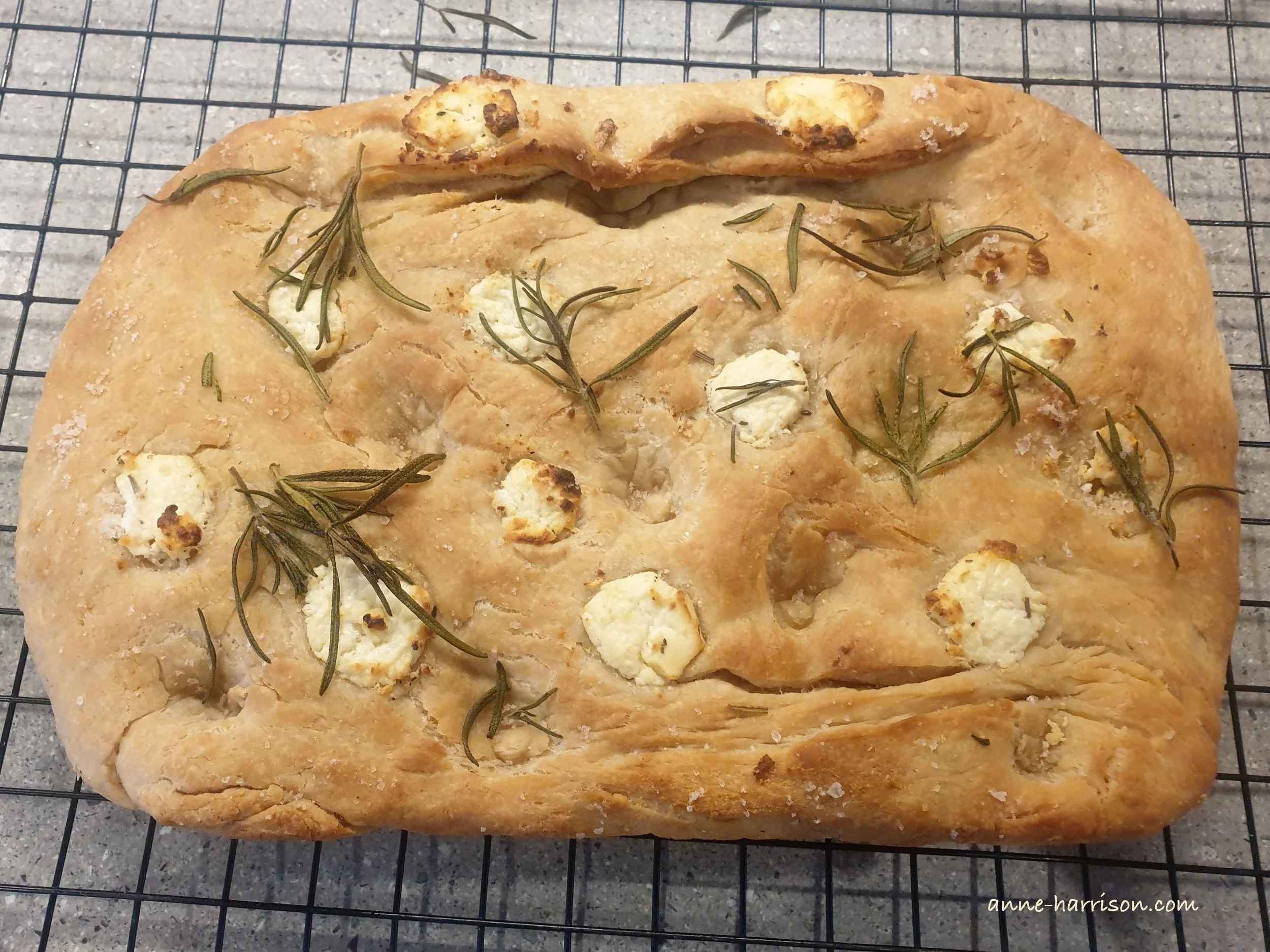 A rosemary and bocconcini focaccia, cooling on an oven rack.