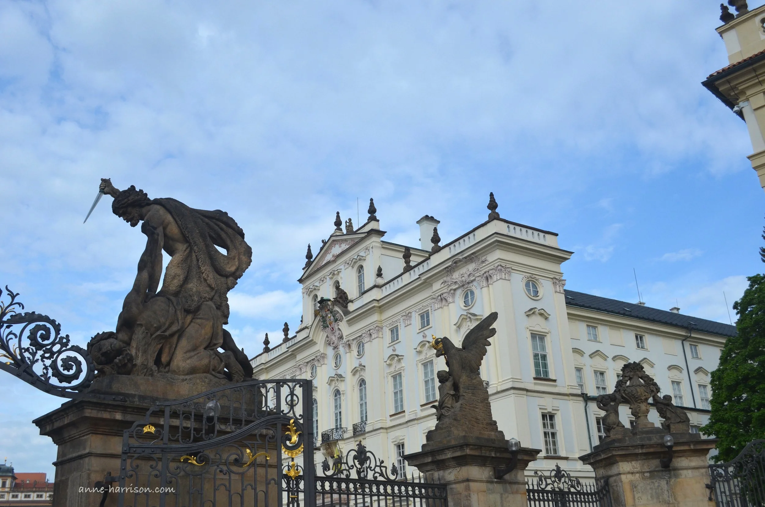 Statues in front of Prague Castle, with a blue sky in the background