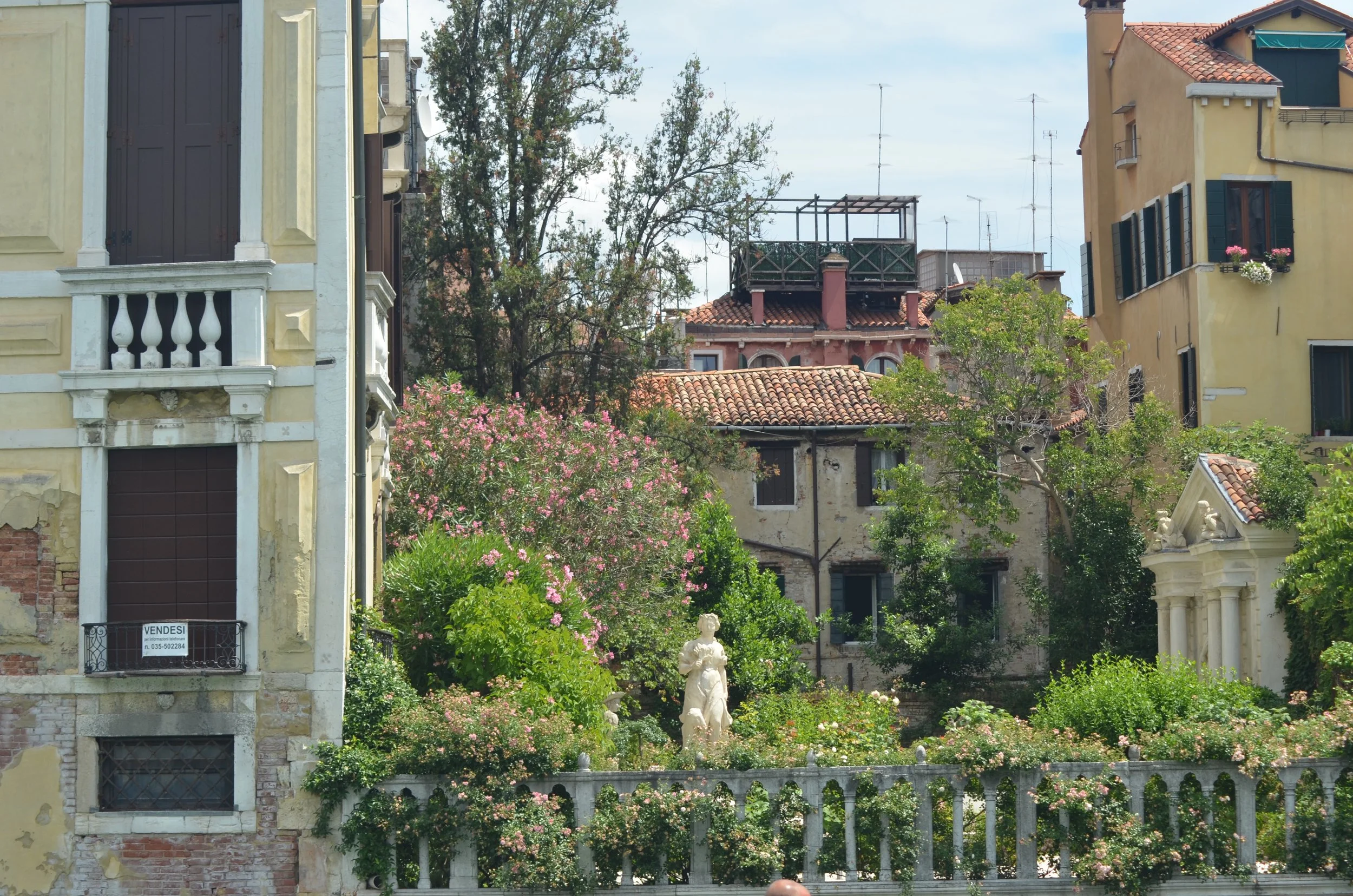 A white statue surrounded by flowers in a courtyard in Venice