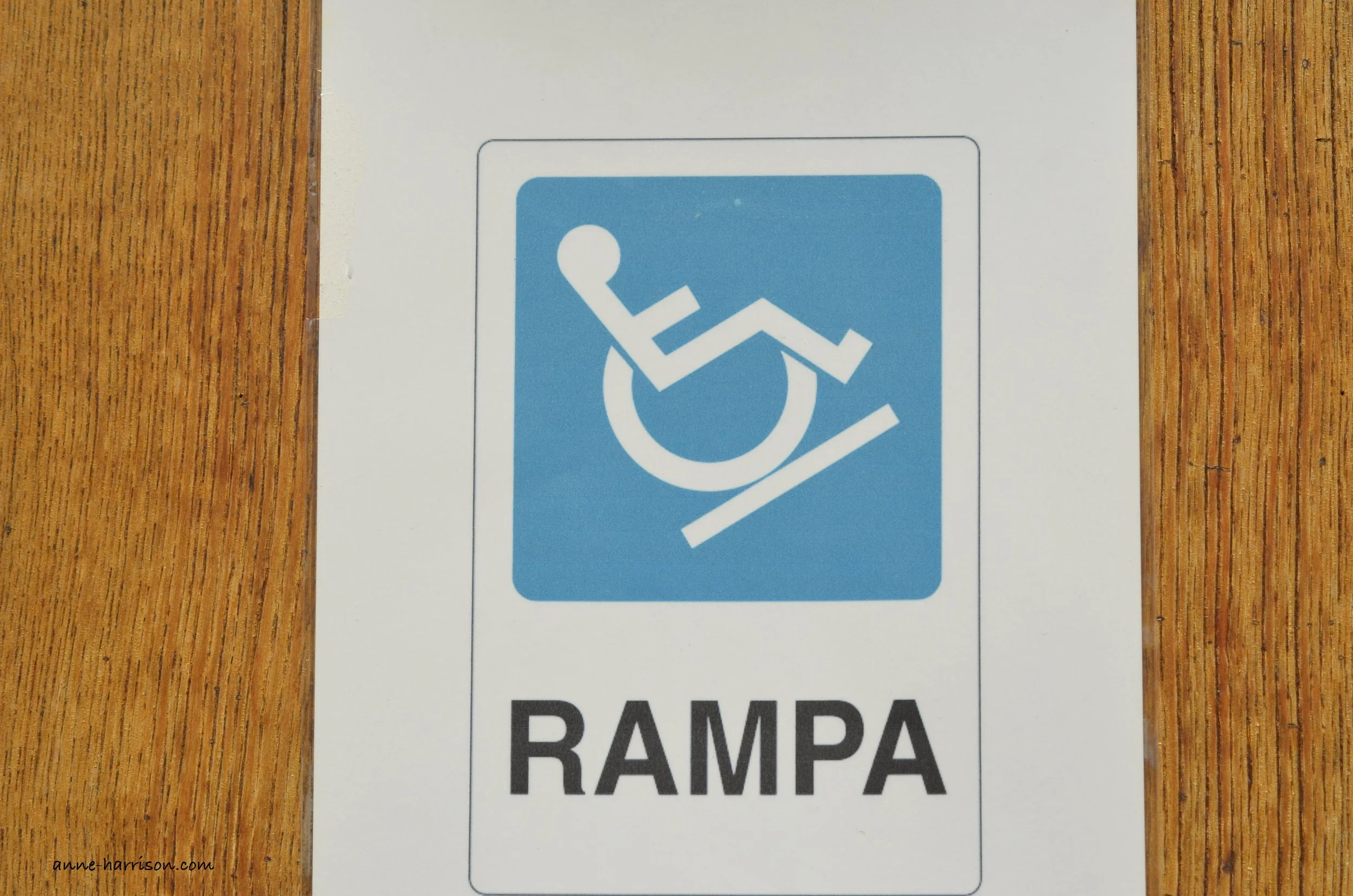  A sign showing disabled access as a wheelchair going up a very steep ramp. 