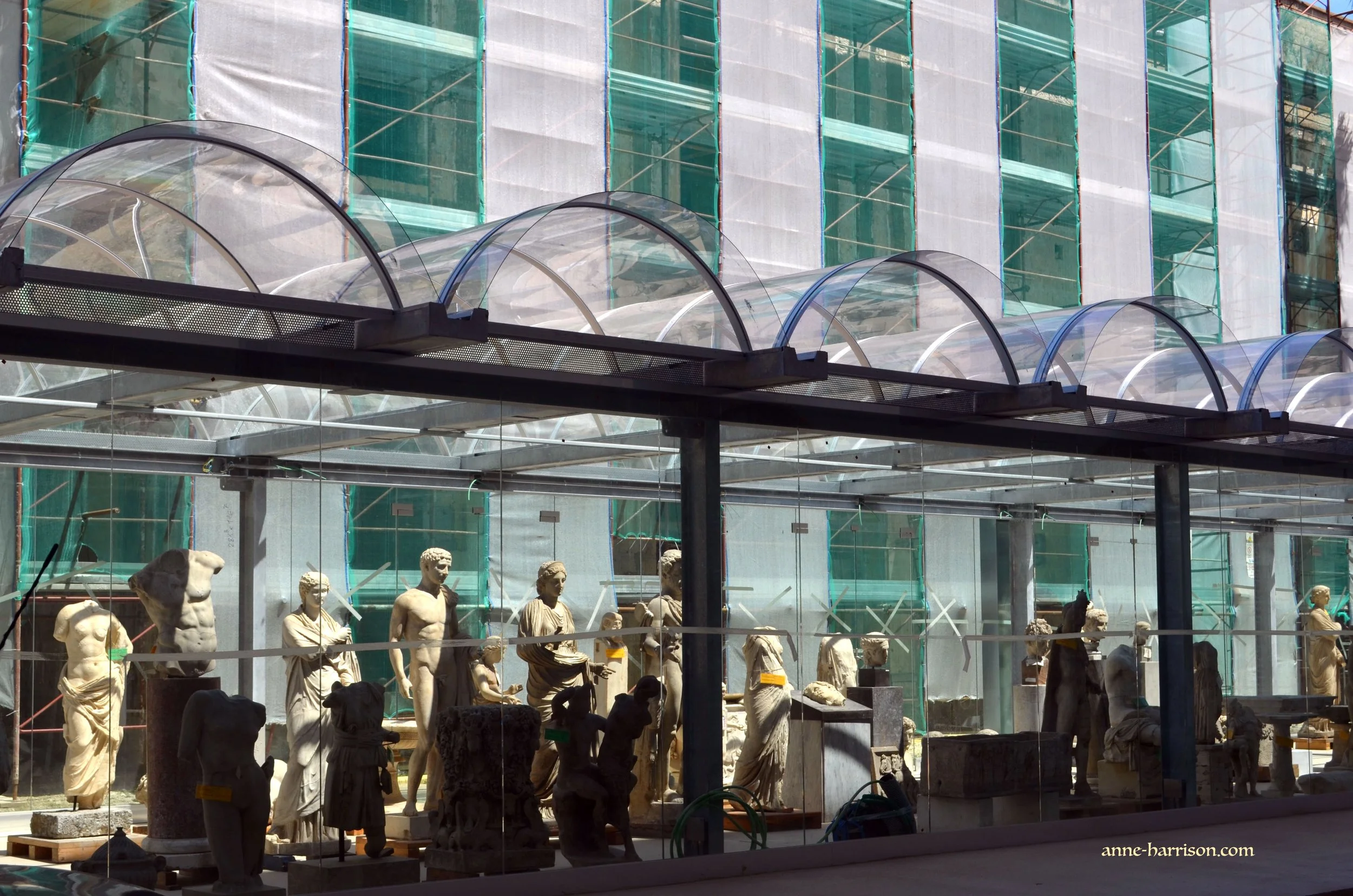 A row of ancient marble statues behind glass lining a walkway
