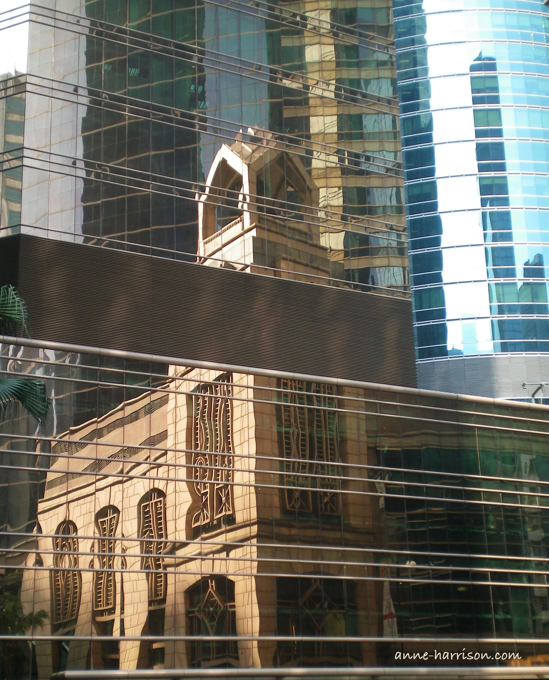 A sanstone church is reflected in the windows of a sky scrapper