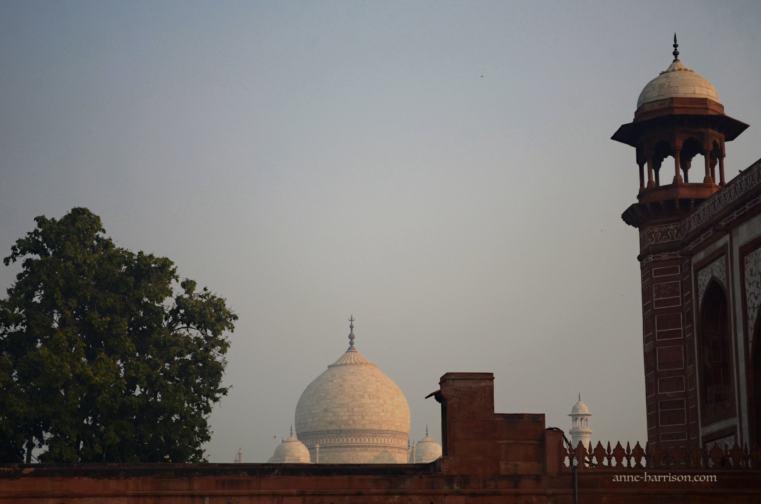 the dome of the Taj Mahal appearing over a red wall