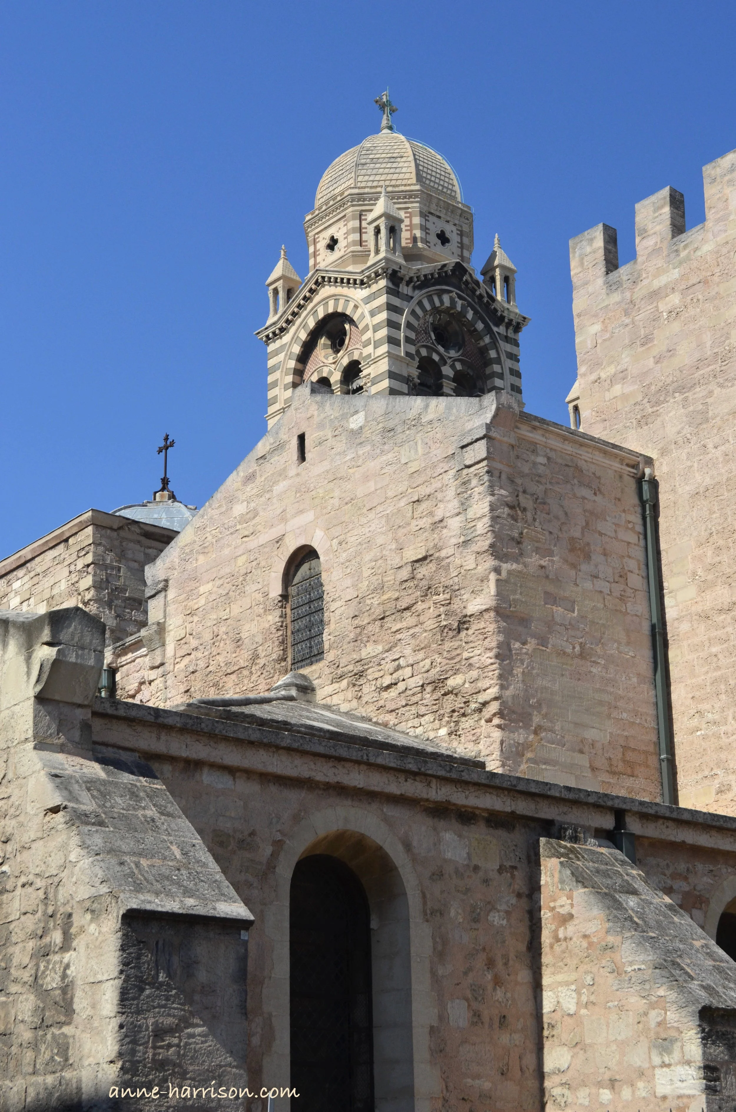 The old stonework of Marseille's Ancienne Cathedral de la Major gleams in the sunlight. The belltower of stripped marble is topped with a cupola.