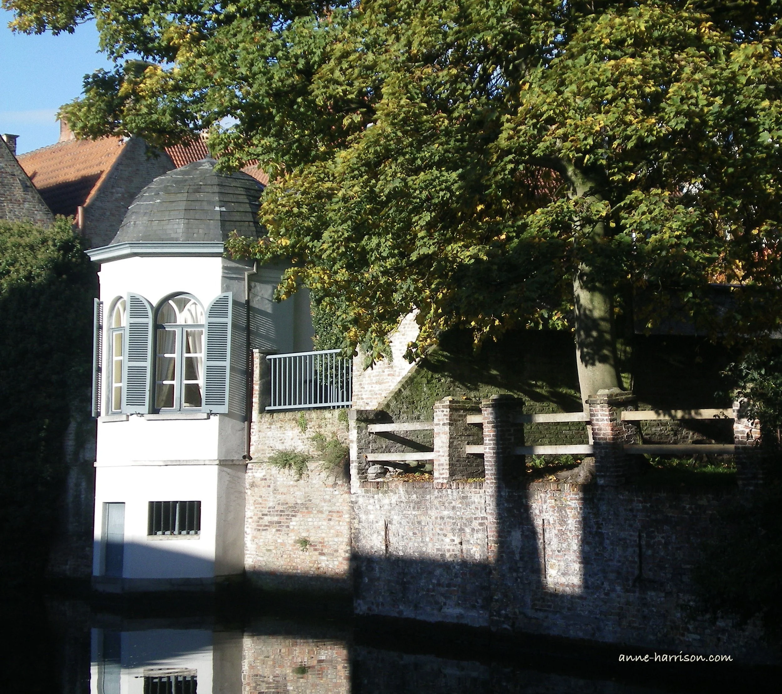 A house with a n octagonal white tower beside a canal