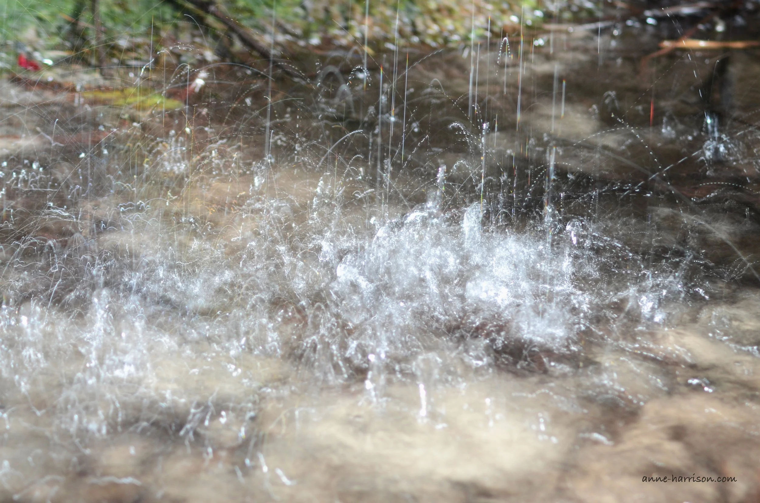 Rain flooding a street, the droplets splashing into the air