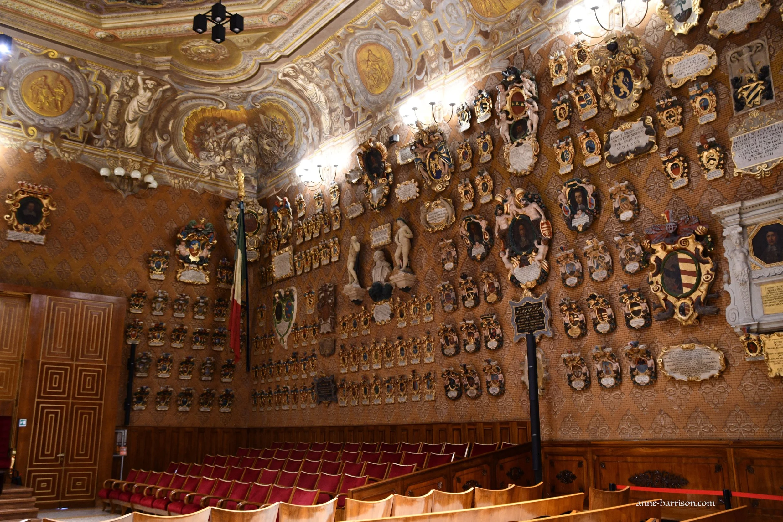 A lecture theatre, with the walls covered in plaques and coat of arms
