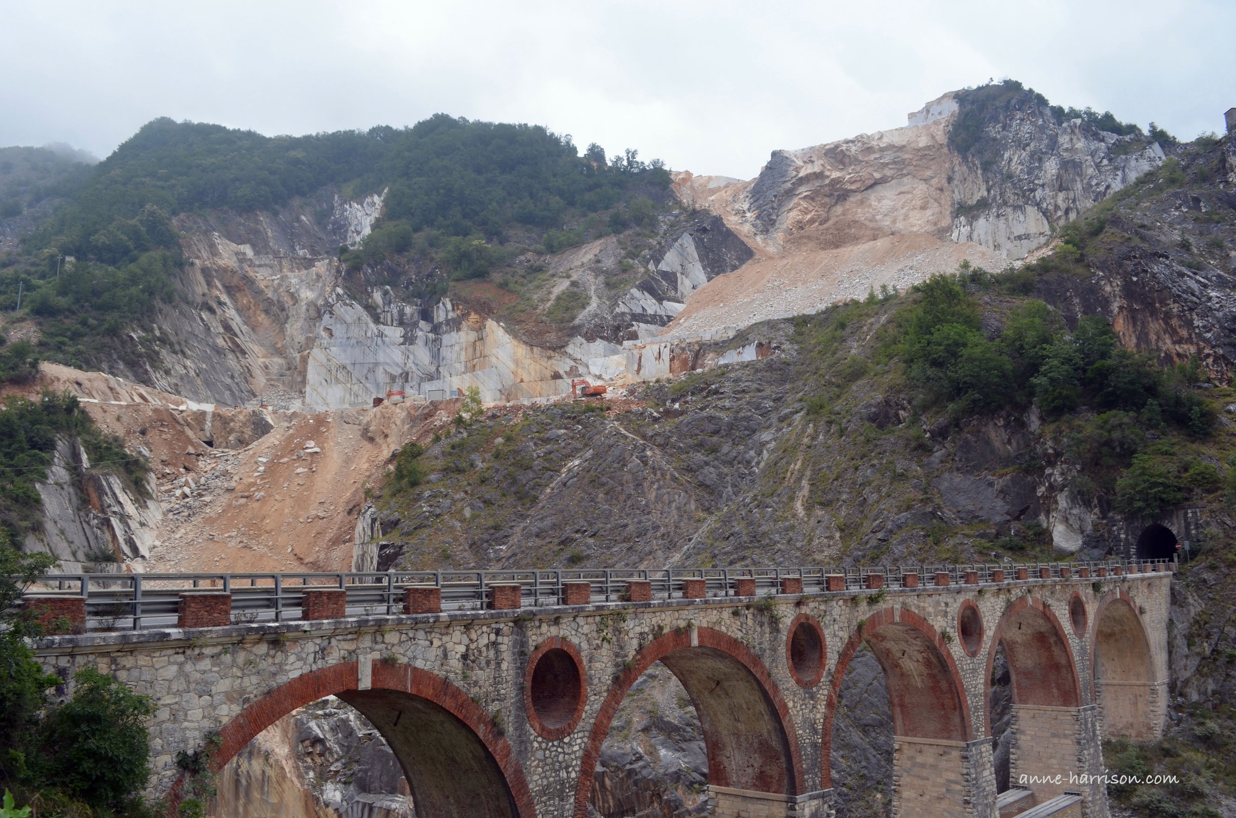 An arched bridge once used by trains to transport marble. The quarry is in the background