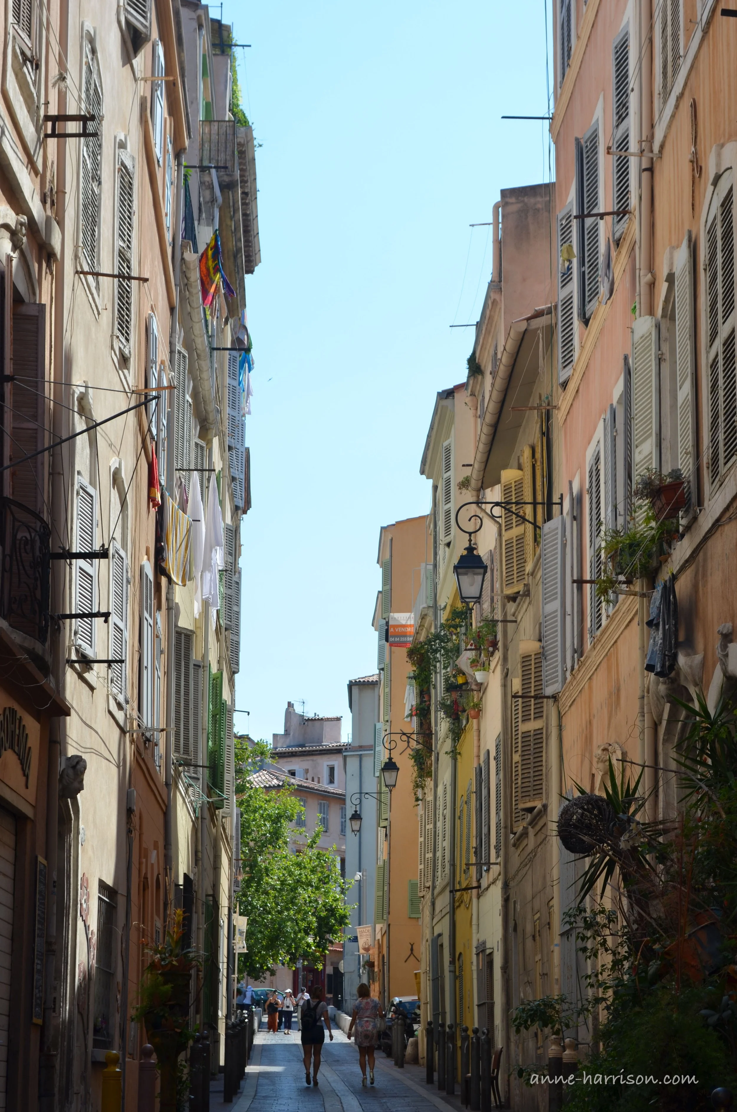Tourists walking along a street lined with colourful buildings in Le Panier, Marseilles.