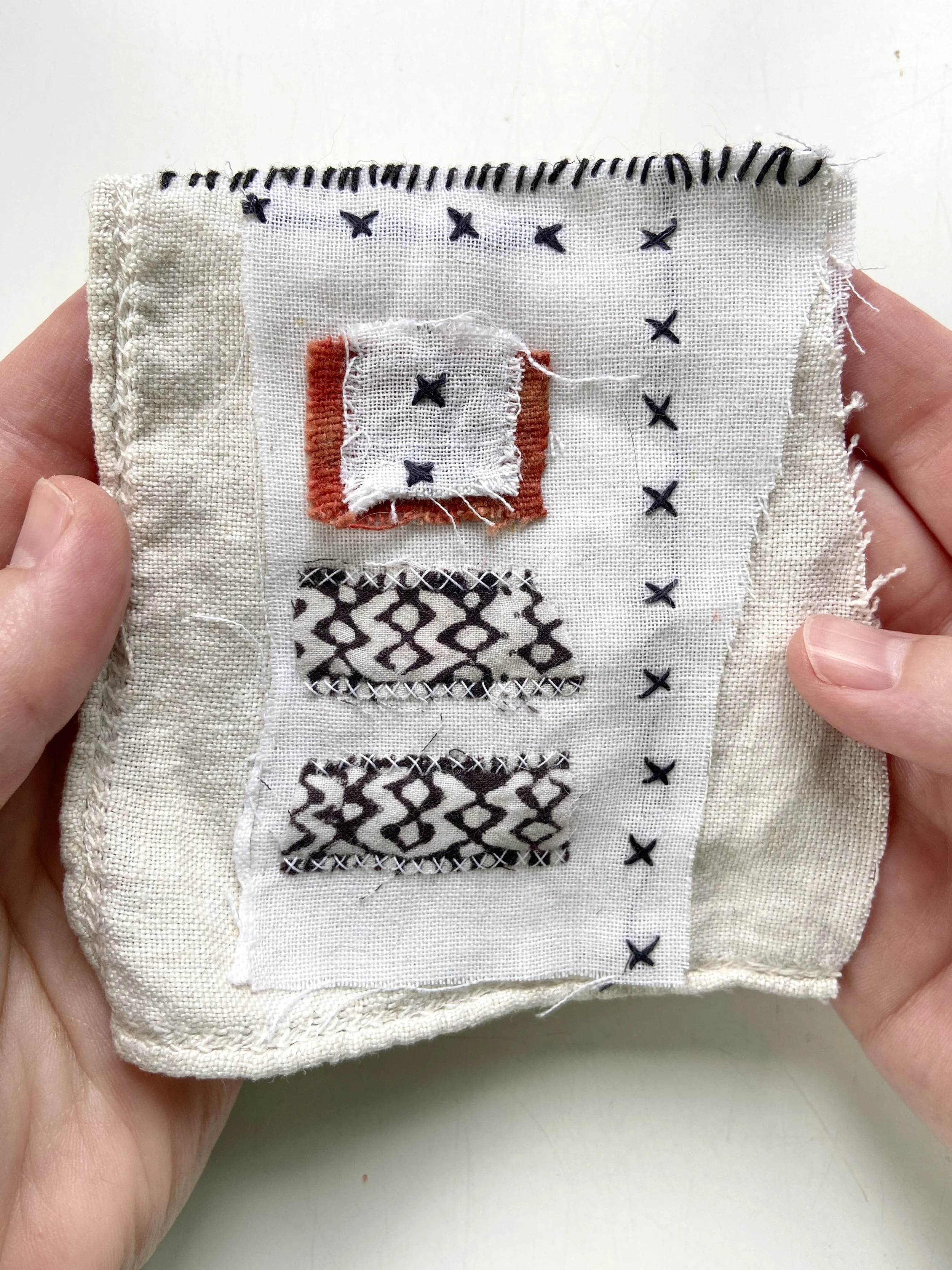 Fabric meditation book made by Emma Freeman using vintage cross stitched embroidered textiles, repurposed handmade batik clothing, a fragment of red dyed cotton from a vintage Peruvian woven wall hanging, vintage linen tablecloth scraps, hand spun na
