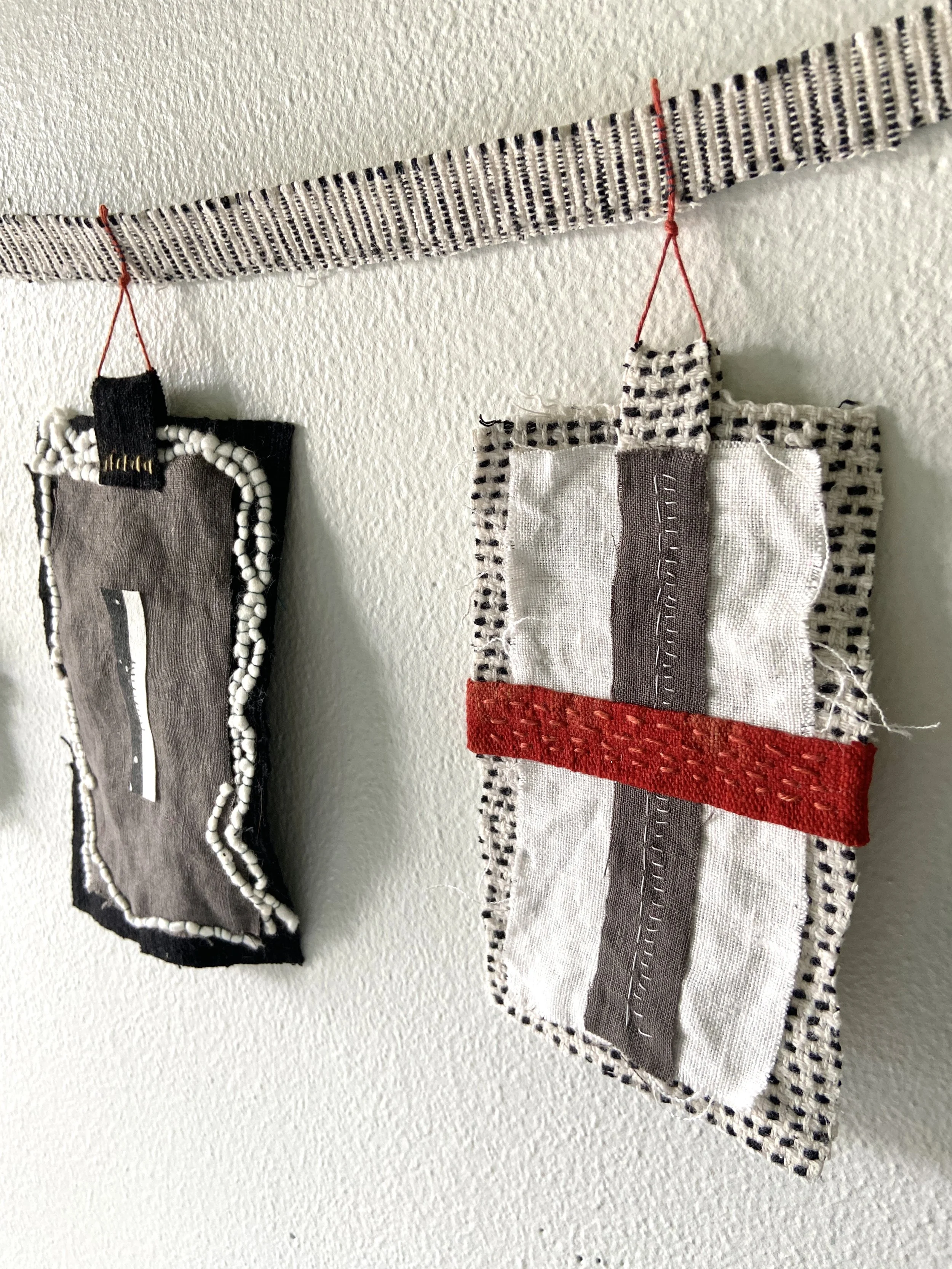 Mixed media wabi sabi prayer flags created by Emma Freeman in Wisconsin using repurposed fabric, textiles, found nature, slow stitching, and hand embroidery, mark making, abstract art compositions and expressions, black, white, red and grey prayer fl