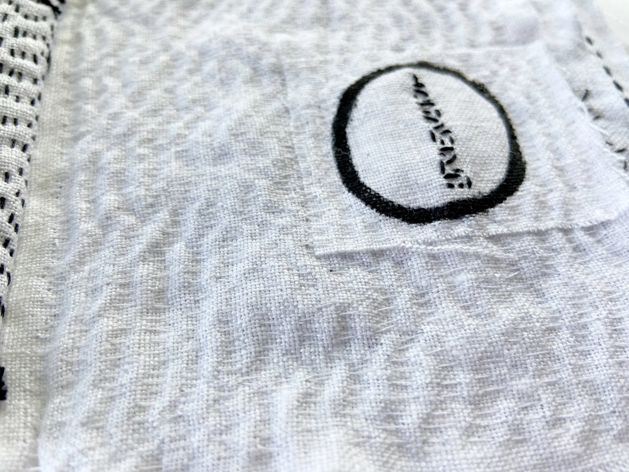 Black and white textile meditation book with ensō circle painting on white linen and slow, hand stitching seed stitch made by Emma Freeman, contemplative mixed media artist and teaching artist in Wisconsin. Hand painted textiles, textile artist, fabr