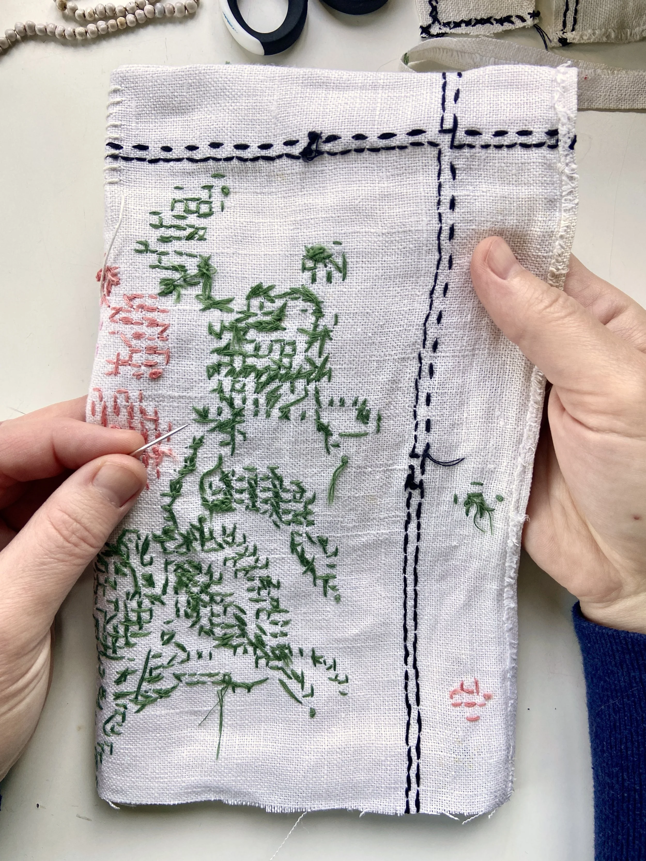 Vintage cross stitched embroidery linen tablecloth transformed into a slow stitched fabric meditation book by Emma Freeman, contemplative textile artist and mixed media artist in Wisconsin. She uses appliqué techniques and other intuitive hand embroi
