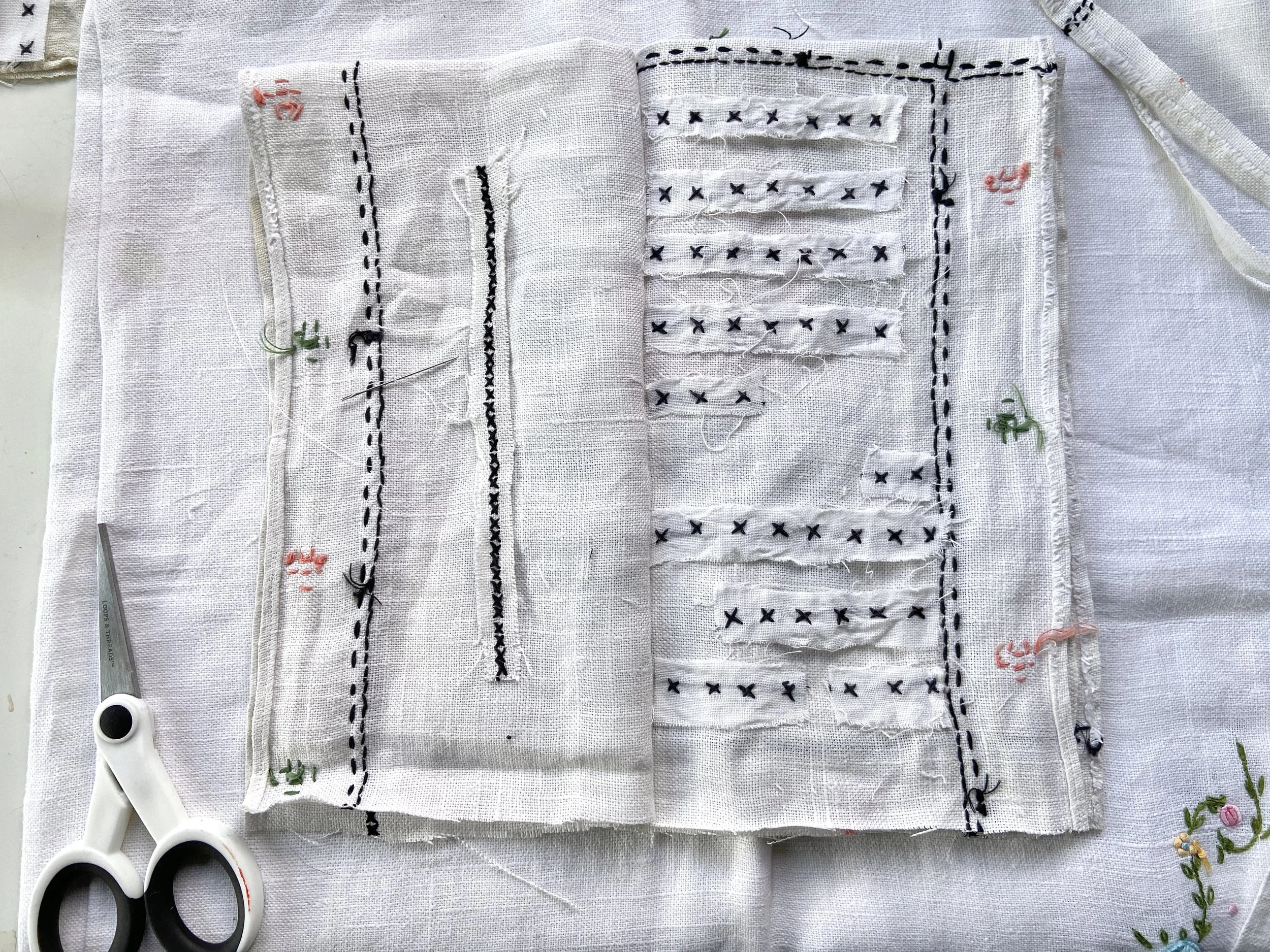 Vintage cross stitched embroidery linen tablecloth transformed into a slow stitched fabric meditation book by Emma Freeman, contemplative textile artist and mixed media artist in Wisconsin. She uses appliqué techniques and other intuitive hand embroi