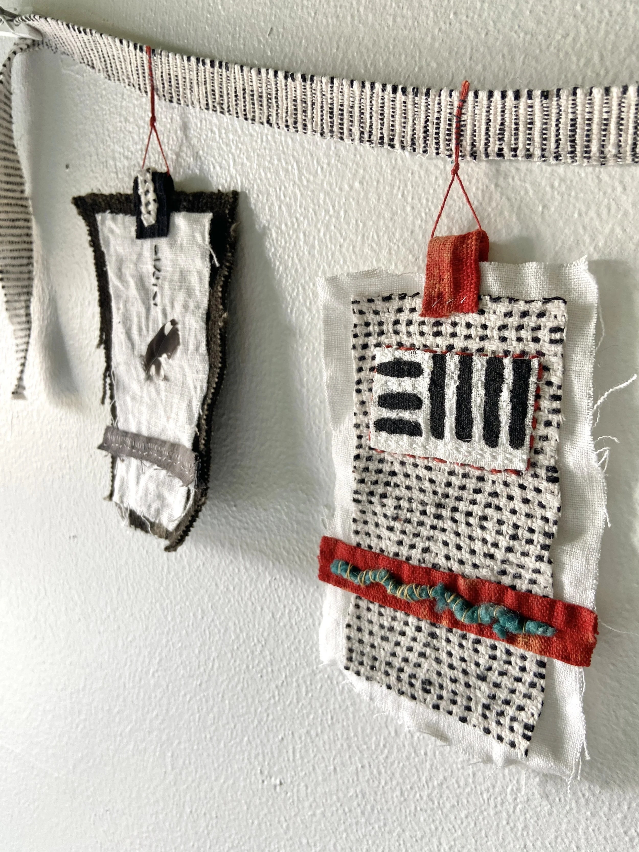 Mixed media wabi sabi prayer flags created by Emma Freeman in Wisconsin using repurposed fabric, textiles, found nature, slow stitching, and hand embroidery, mark making, abstract art compositions and expressions, black, white, red and grey prayer fl